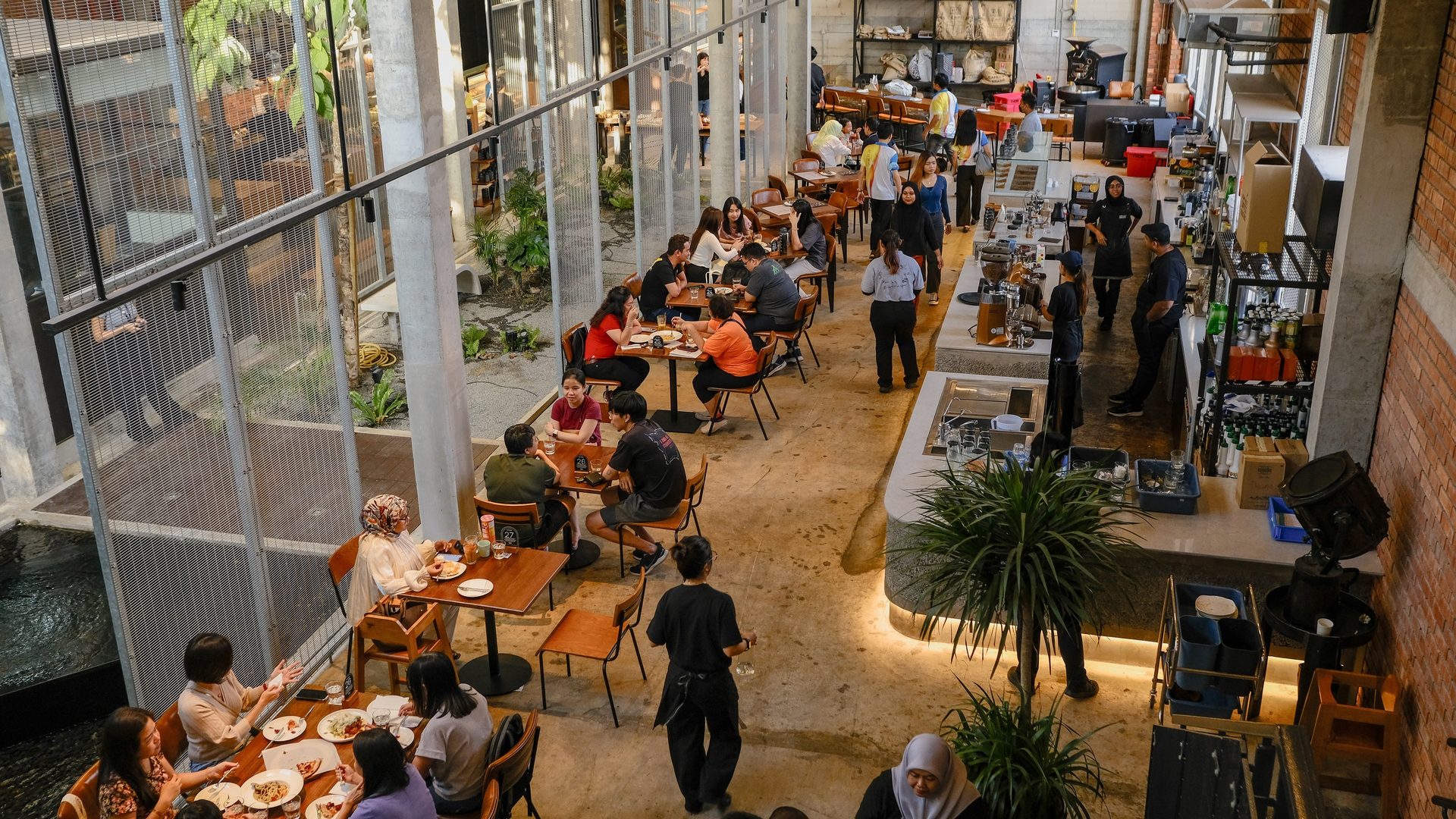 Overhead view of a bustling industrial-chic cafe with people dining and staff.
