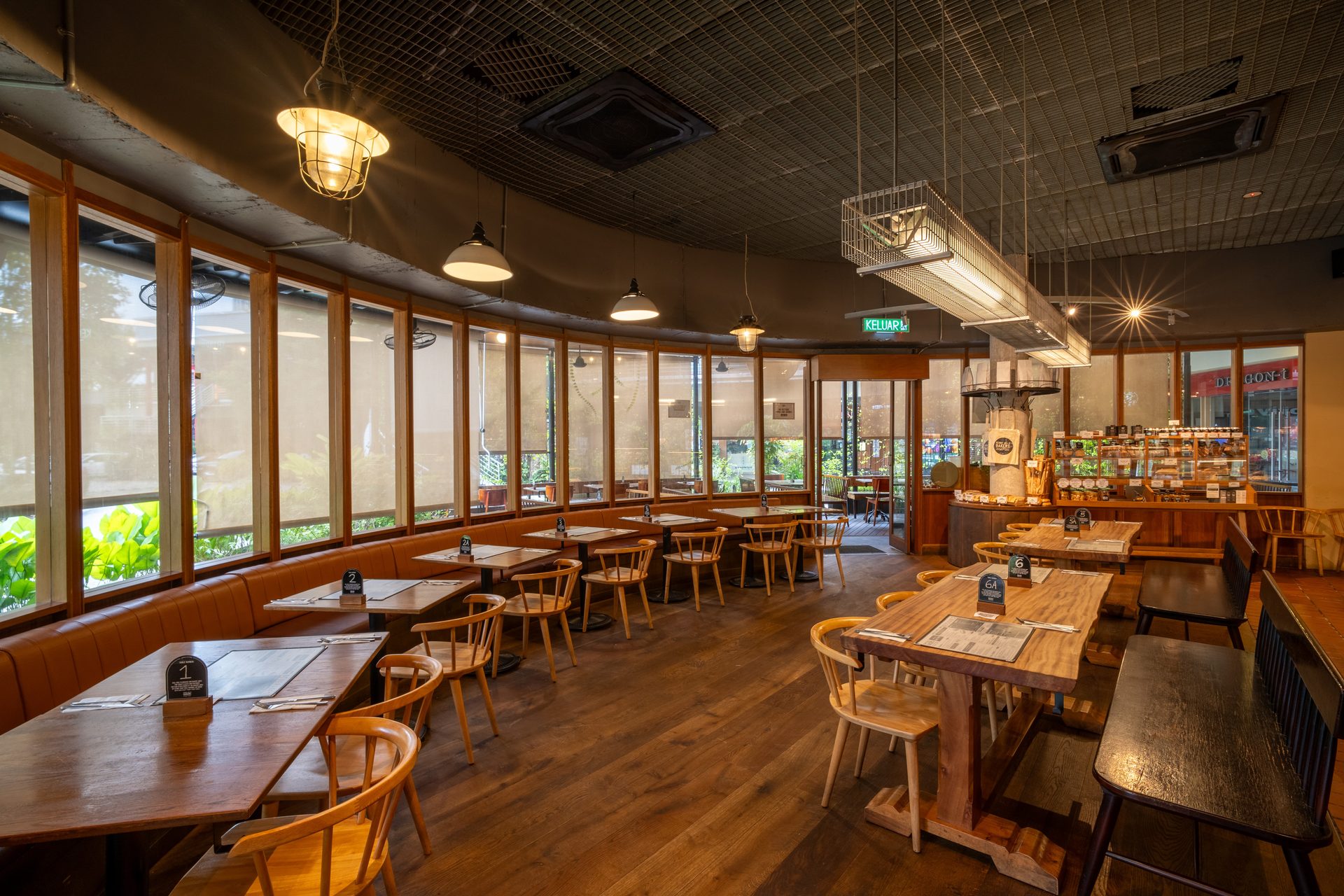 Interior view of a modern restaurant with wooden furniture, large windows, and warm lighting.