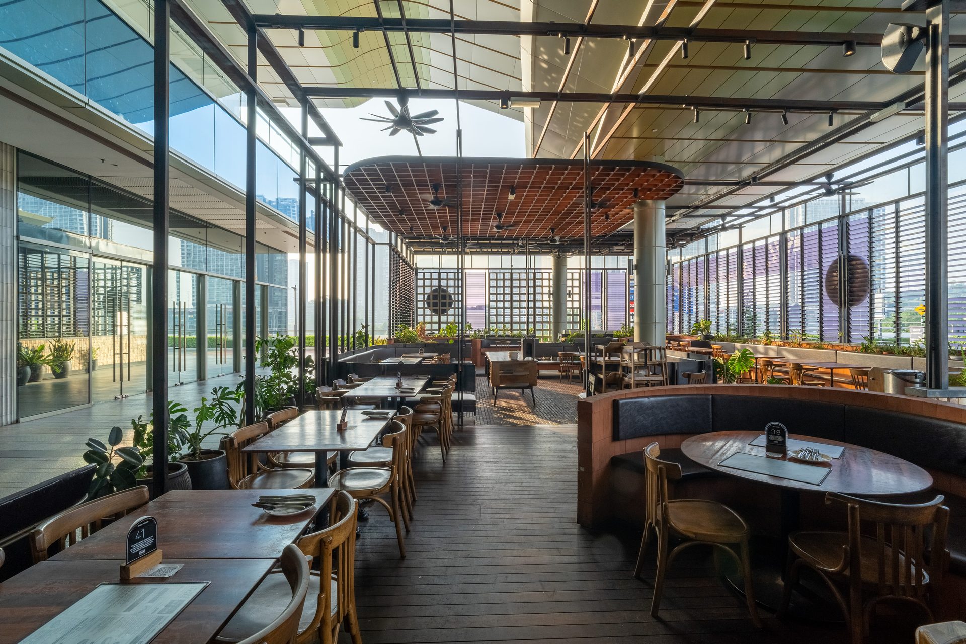Empty, modern restaurant with many tables, chairs, glass walls, and a high ceiling.