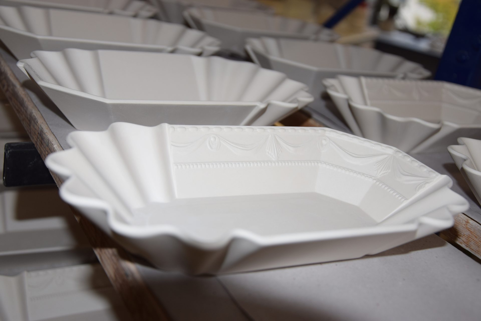 White ceramic dishes with fluted, decorative edges, on shelves.