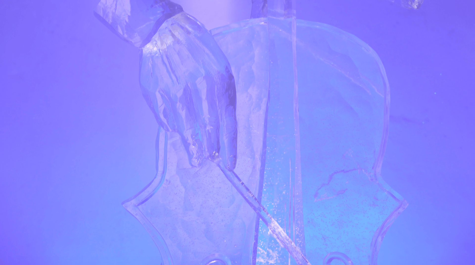 Ice sculpture of a hand playing a cello, illuminated with blue and purple light.