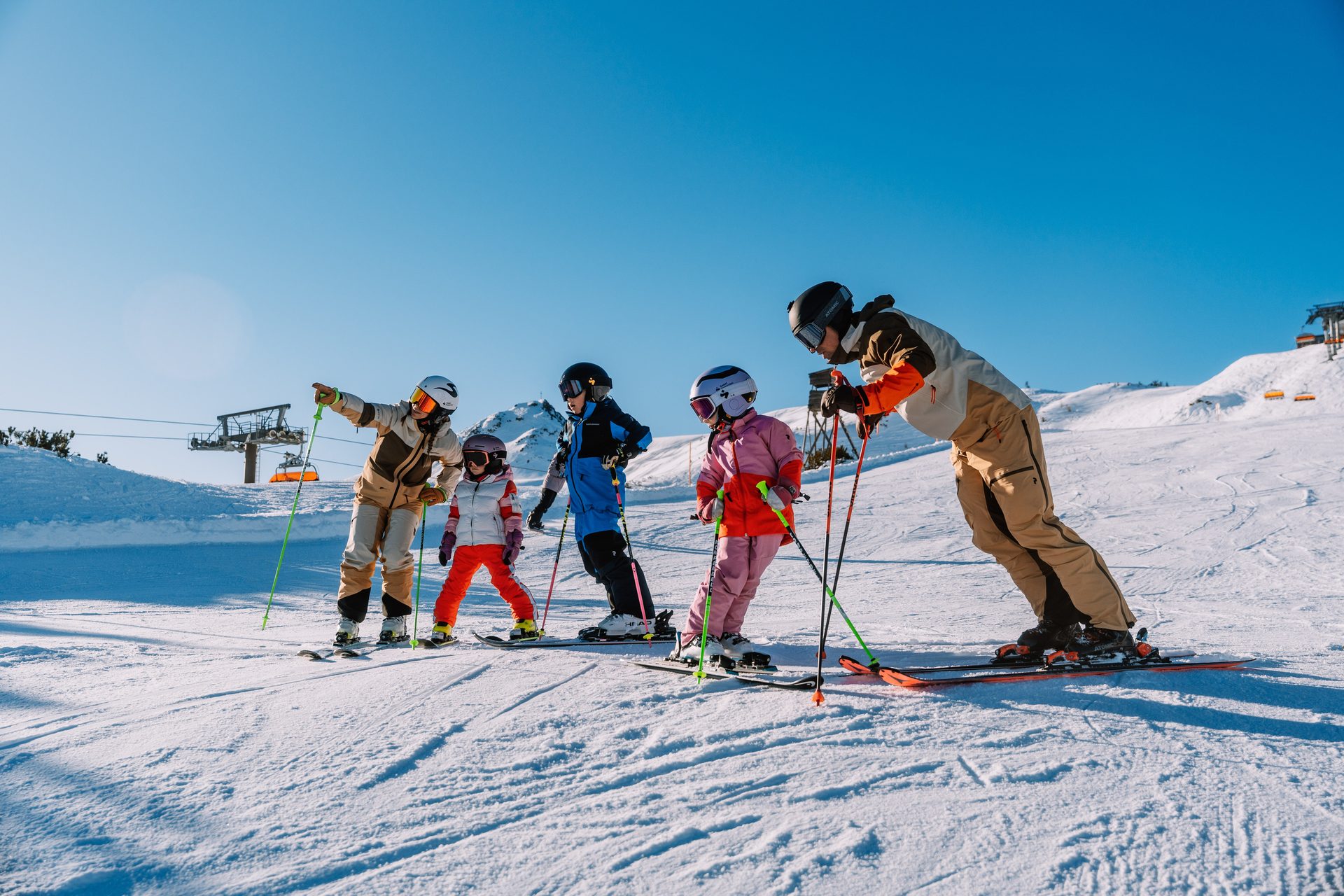 A family, including adults and children, on skis and in ski gear on a snowy mountain slope.