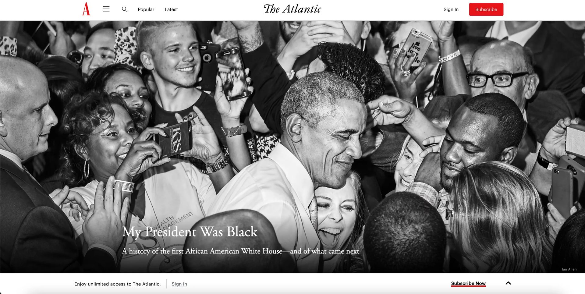 A black and white photo of Barack Obama smiling and interacting with a diverse, excited crowd of people.