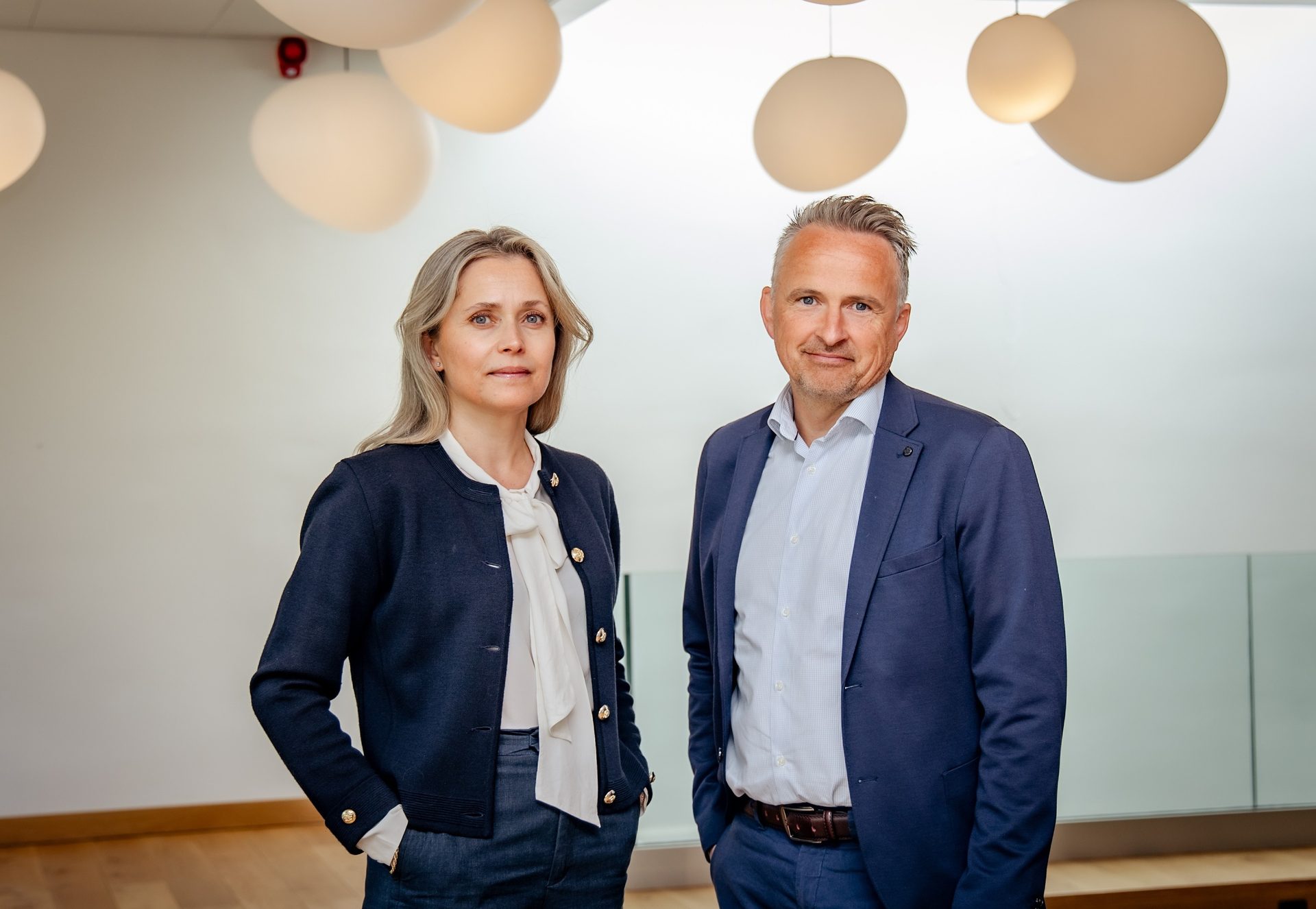 A professional man and woman standing together in a modern office space.