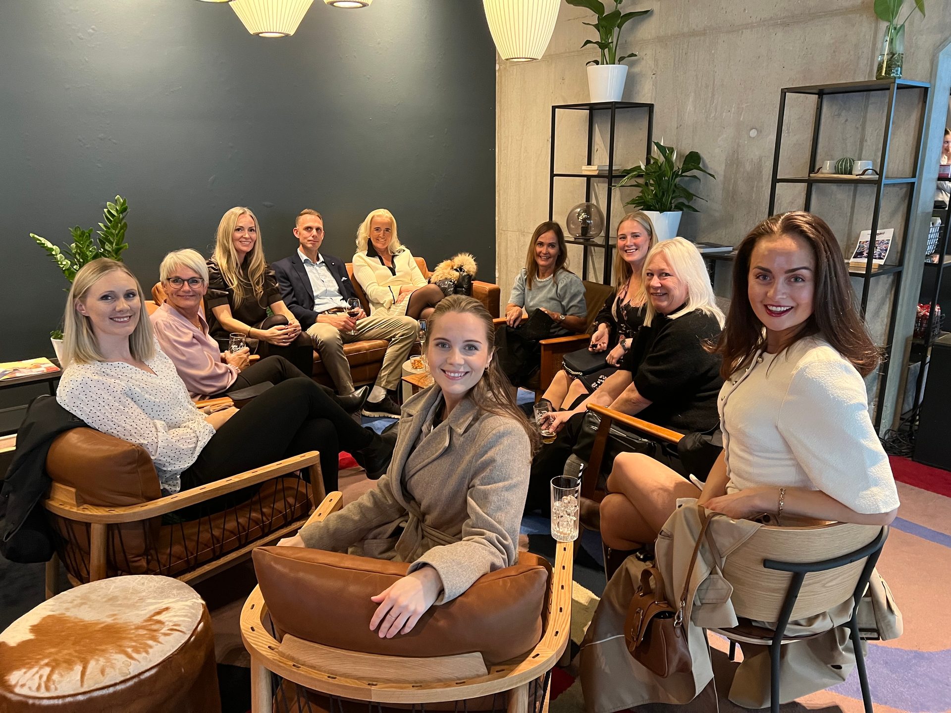 Smiling group of people, mostly women, relaxing in a stylish lounge area.