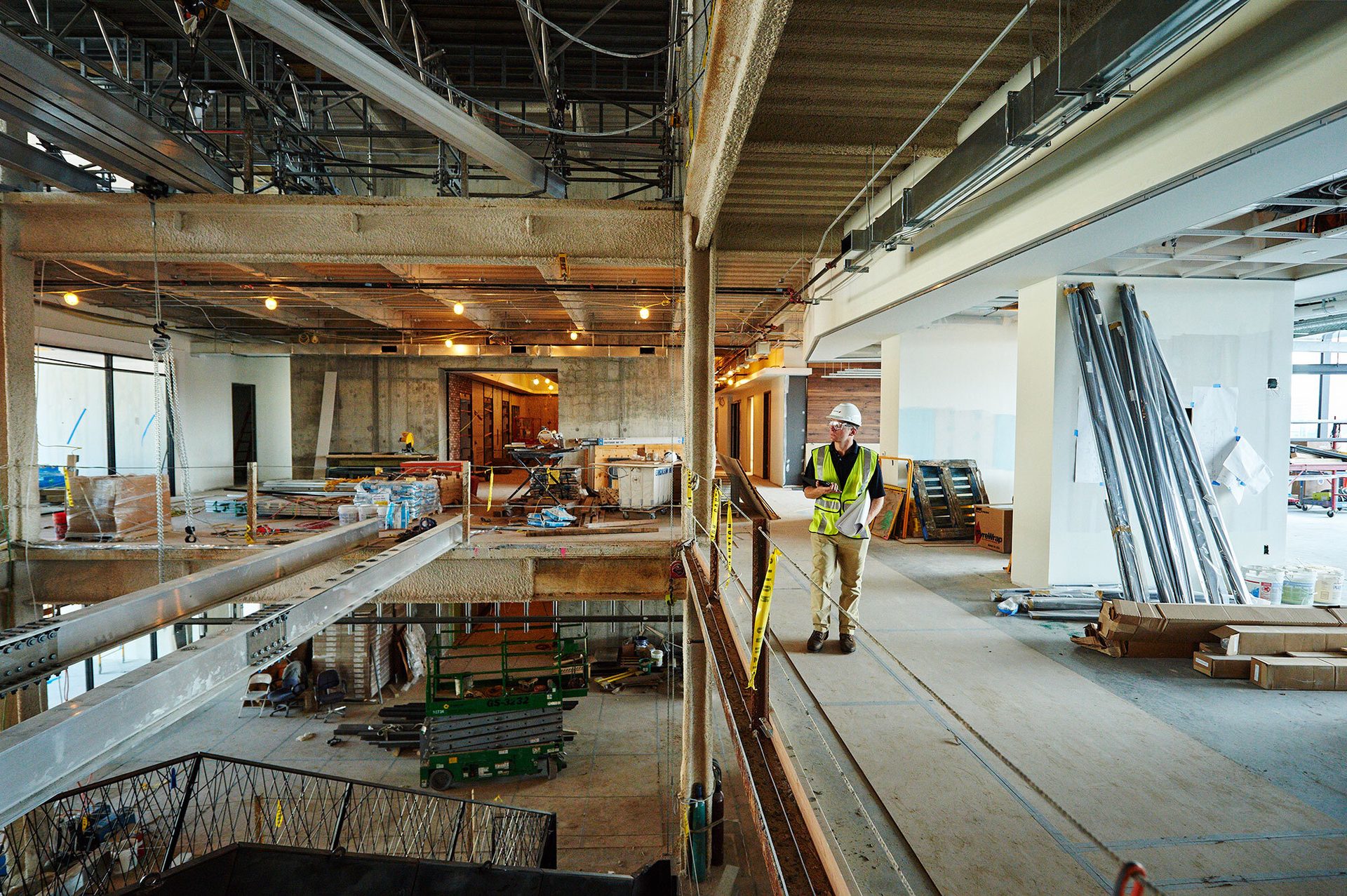 Person in hard hat in multi-level unfinished building interior.