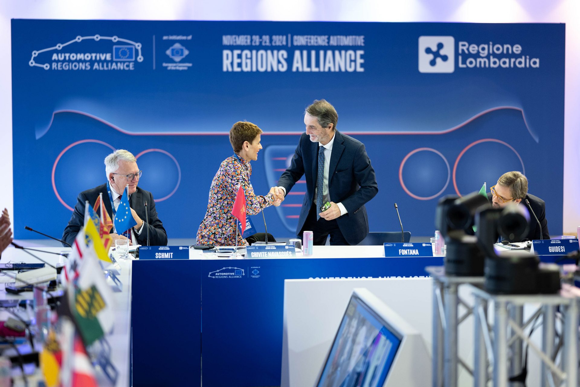 Electronic device, White-collar worker, Outerwear, Suit, Microphone, Coat, Event, Furniture, Spokesperson, Technology