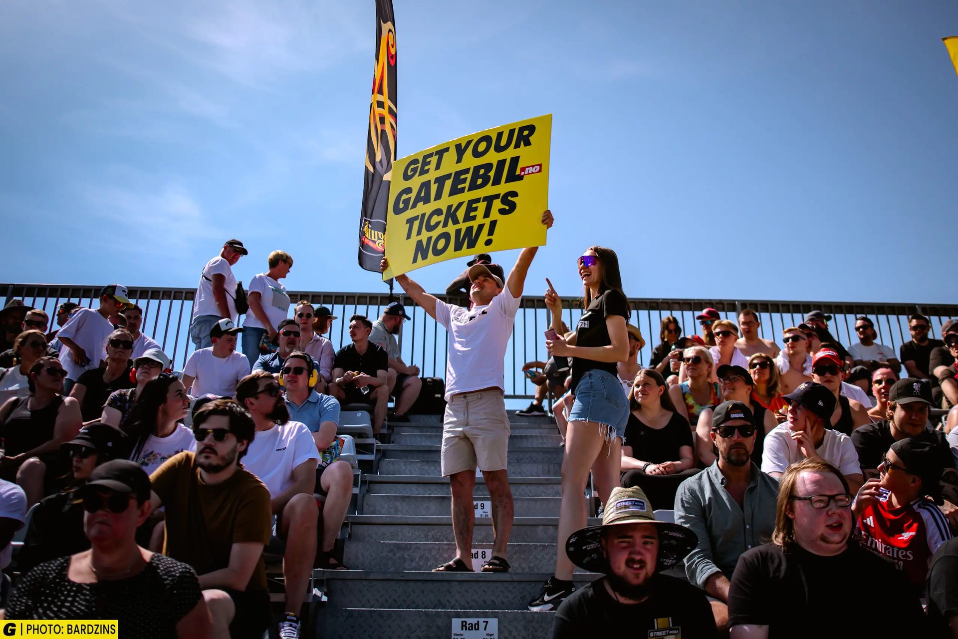 Crowd in bleachers holds sign "GET YOUR GATEBIL.NO TICKETS NOW!".