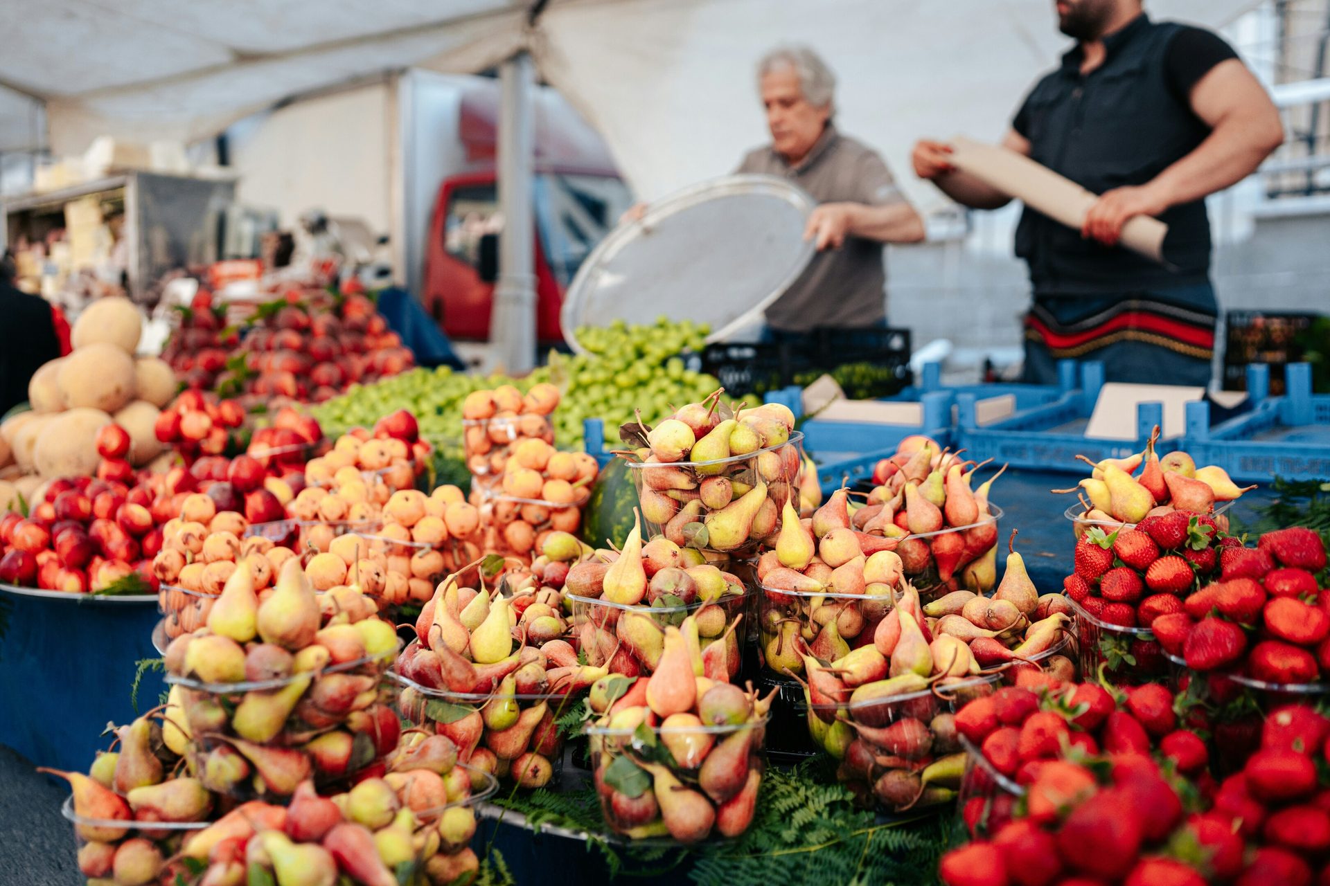 Fresh pears, strawberries, and other fruits displayed at a market stall.