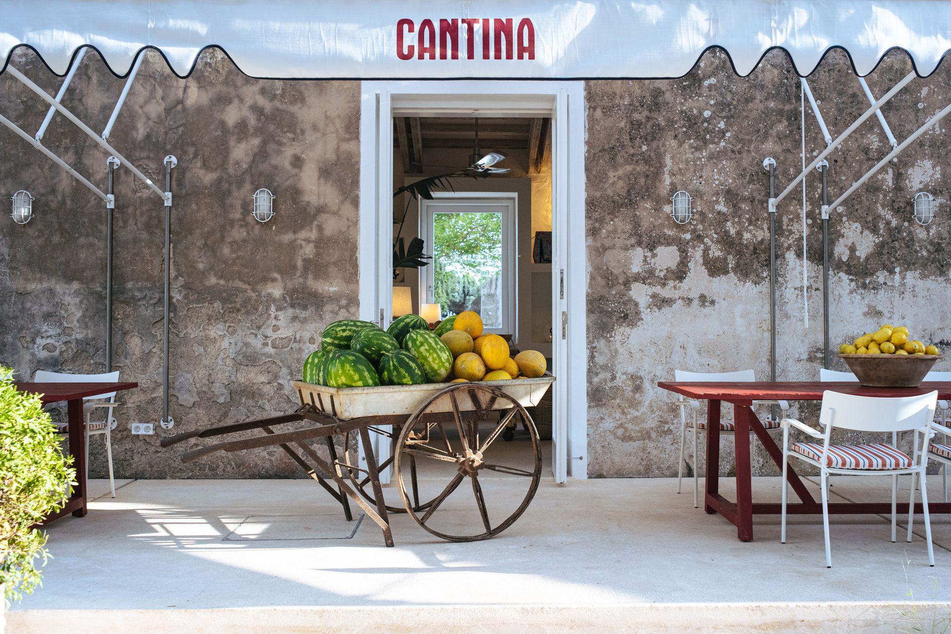 Rustic "CANTINA" entrance with fruit cart and outdoor seating.