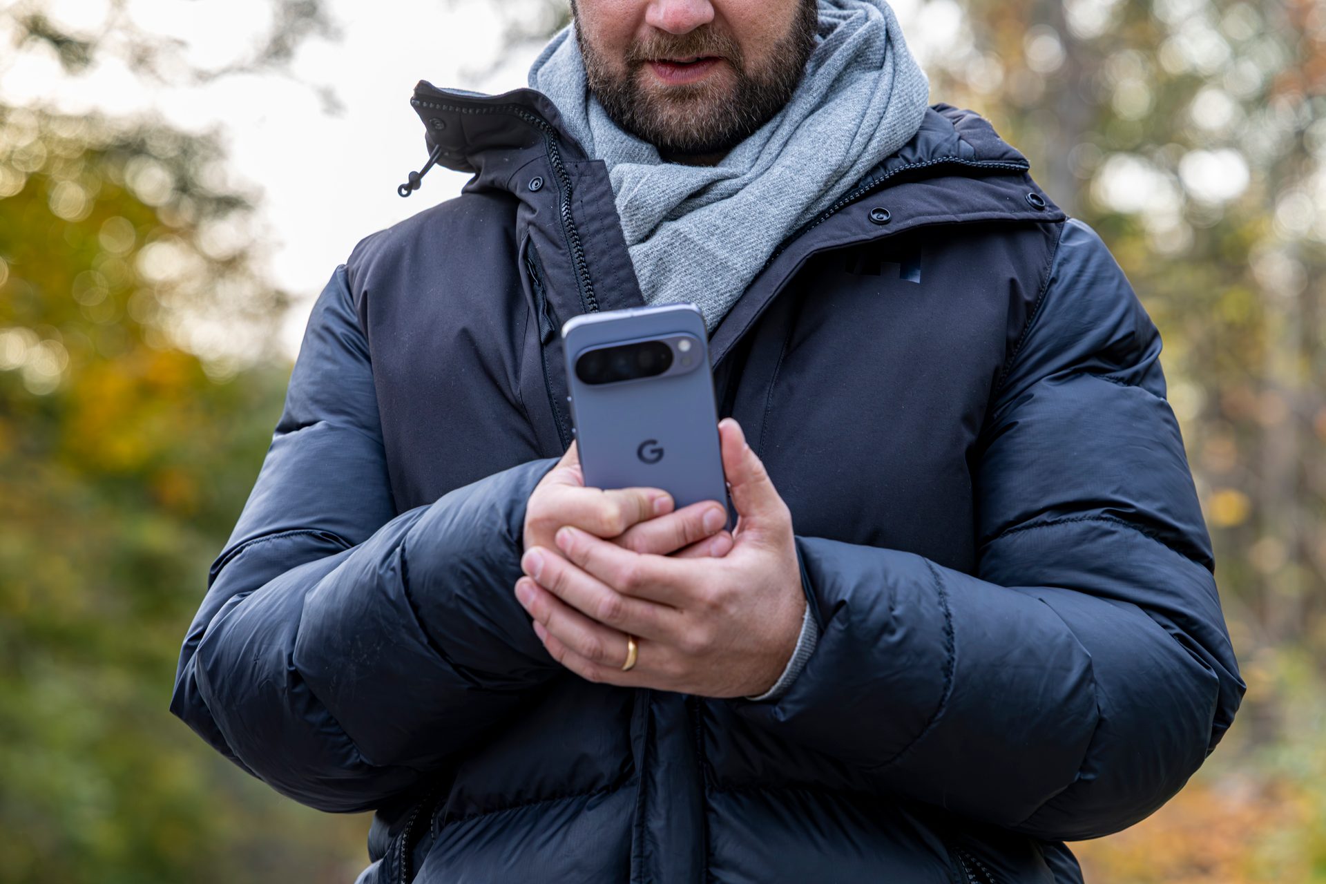 Man in jacket and scarf holds a grey Google Pixel phone.
