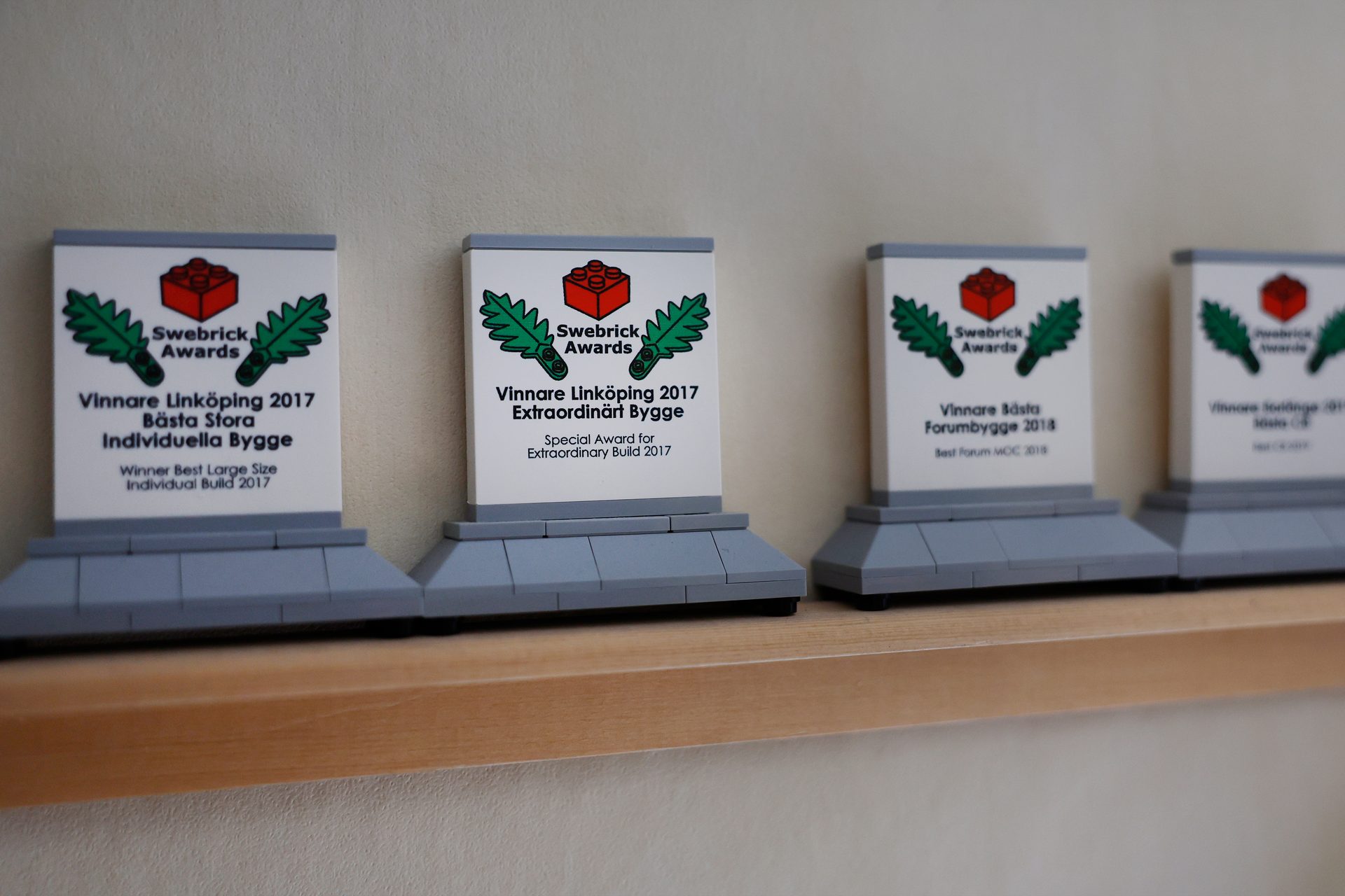 Four LEGO-themed Swebrick awards displayed on a wooden shelf.