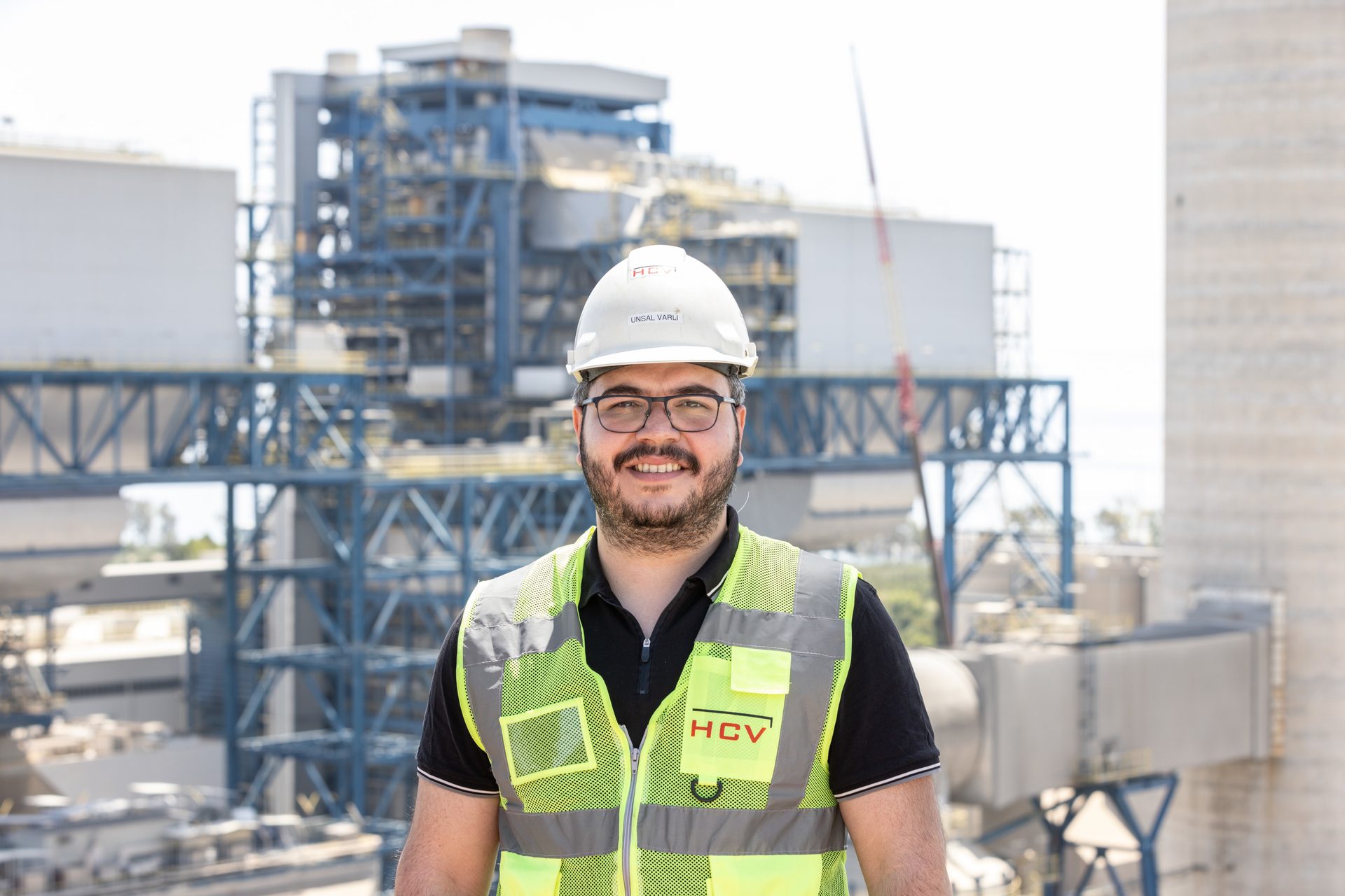 Hard hat, High-visibility clothing, Face, Smile, Workwear, Helmet, Sky, Sleeve, Building, Engineer