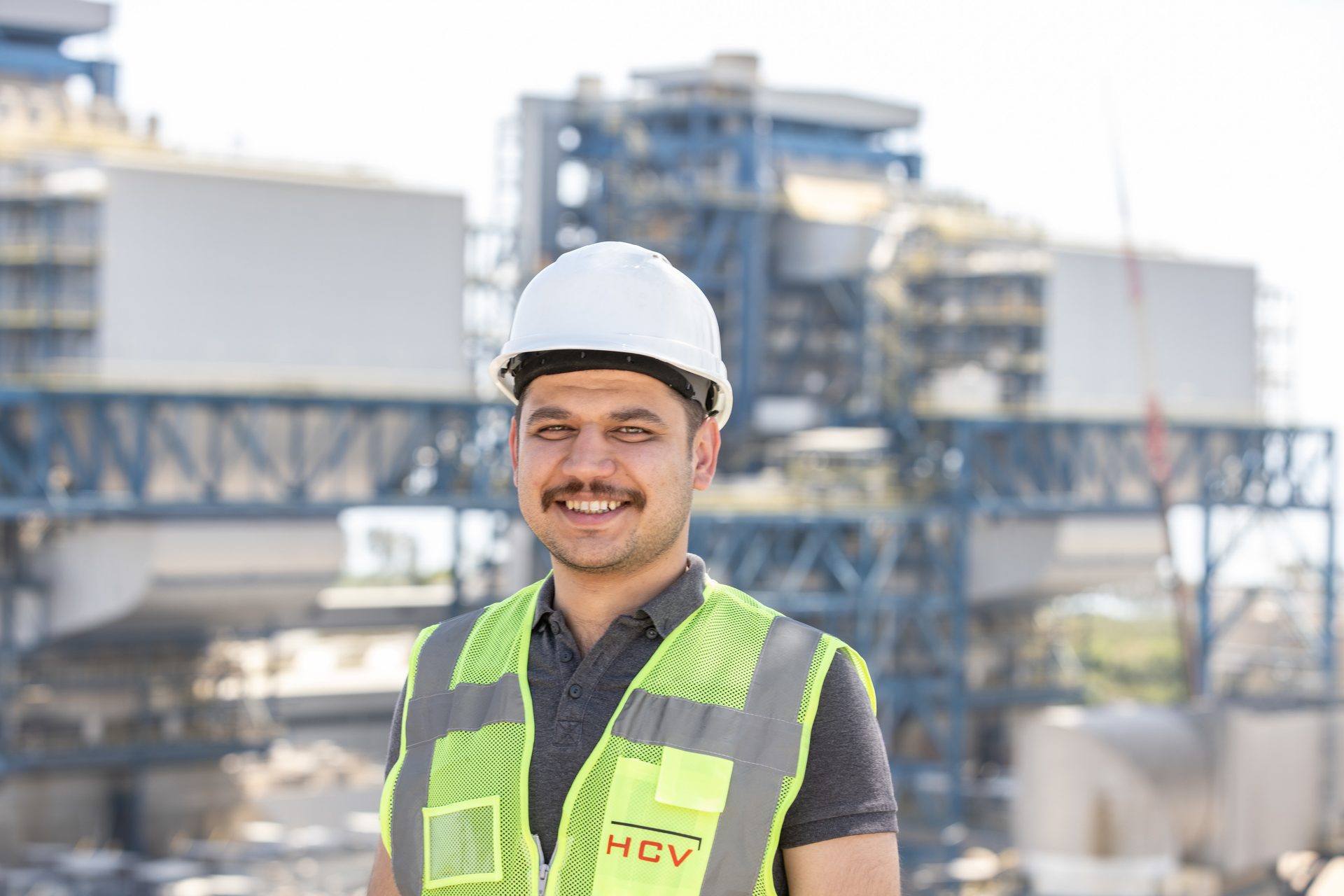 Hard hat, High-visibility clothing, Smile, Workwear, Helmet, Sleeve, Sky, Engineer, Building