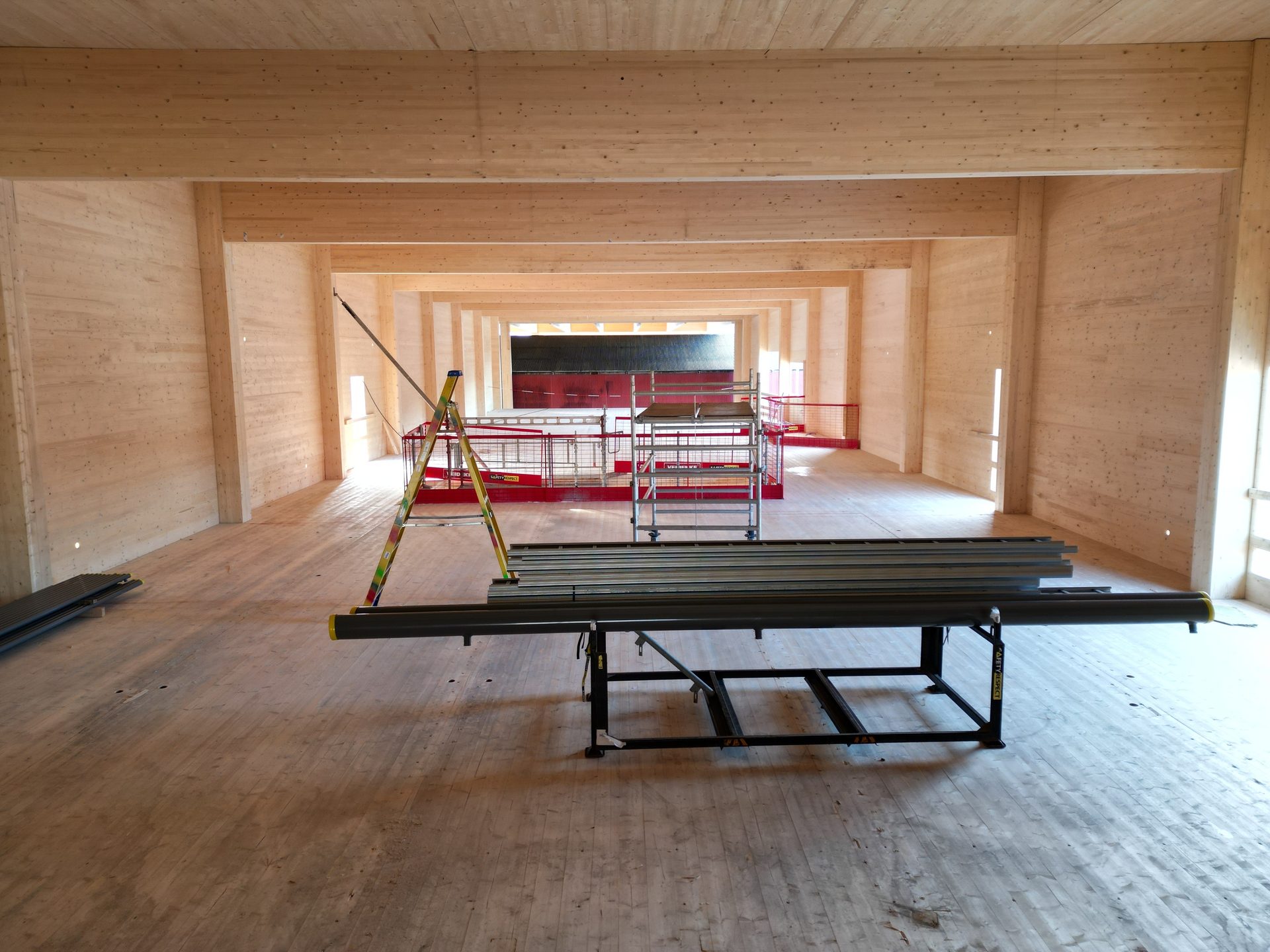 Spacious wood building interior under construction with scaffolding and materials.