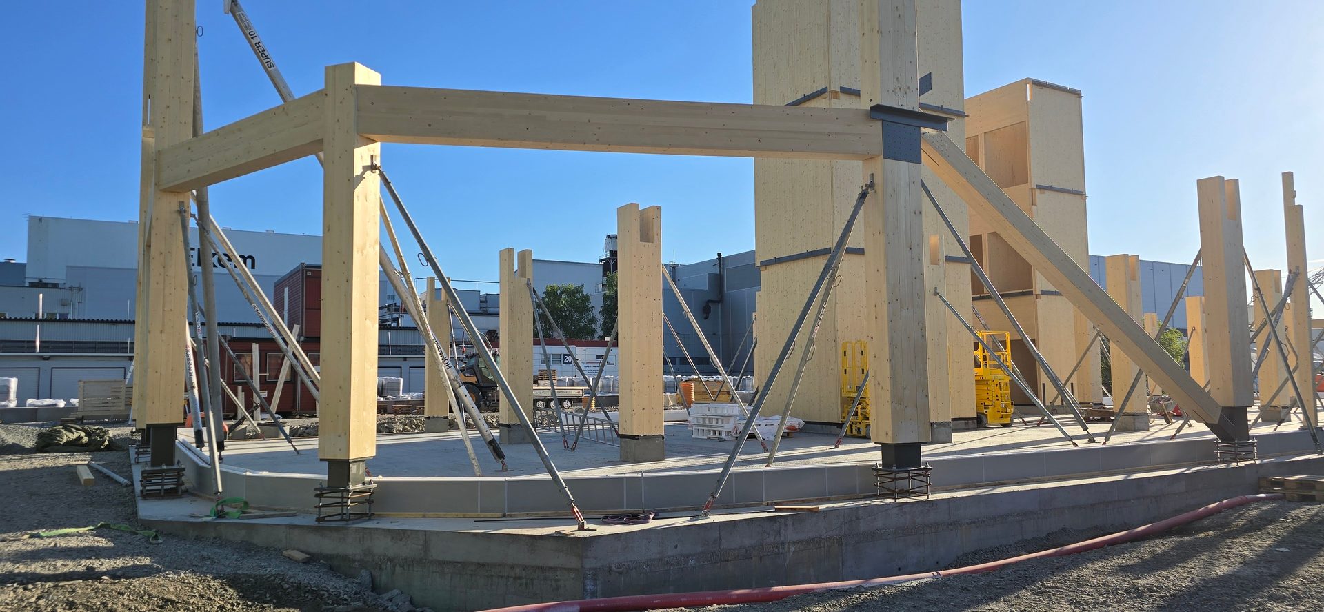 Timber frame building under construction, with wooden columns, beams, and metal props.