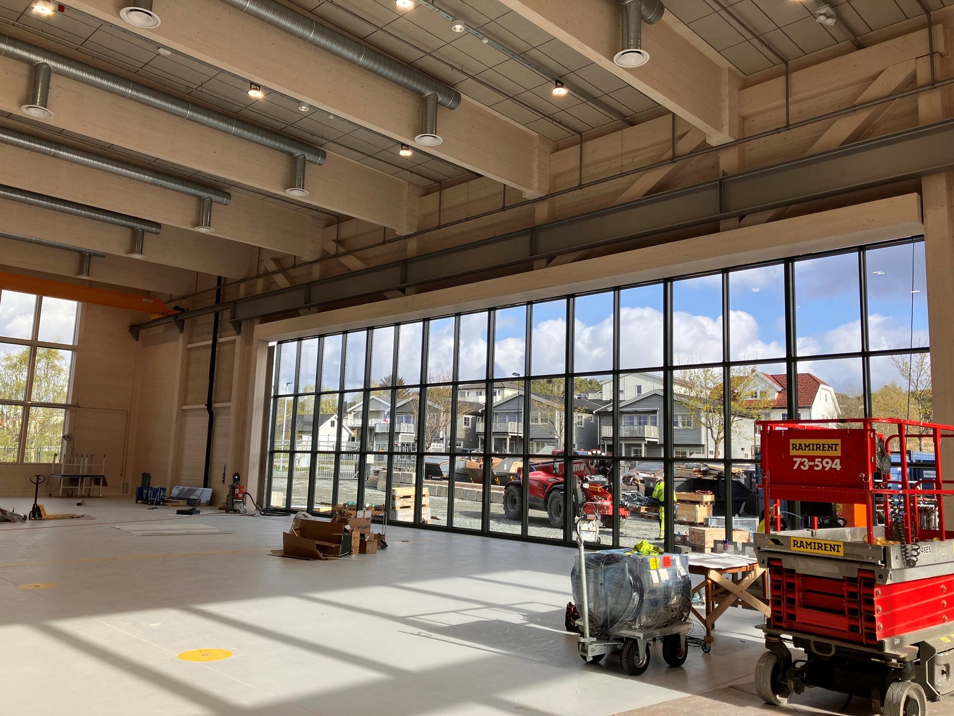 Spacious interior with exposed timber beams, large windows, and construction equipment.