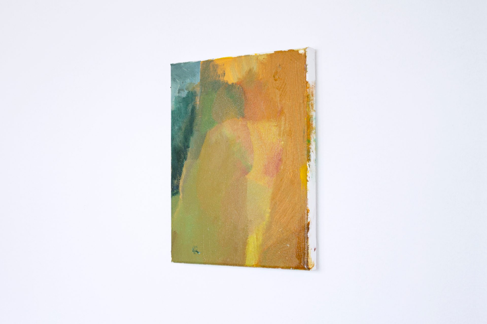 Textured abstract painting in green, yellow, orange, and brown, angled on a white wall.