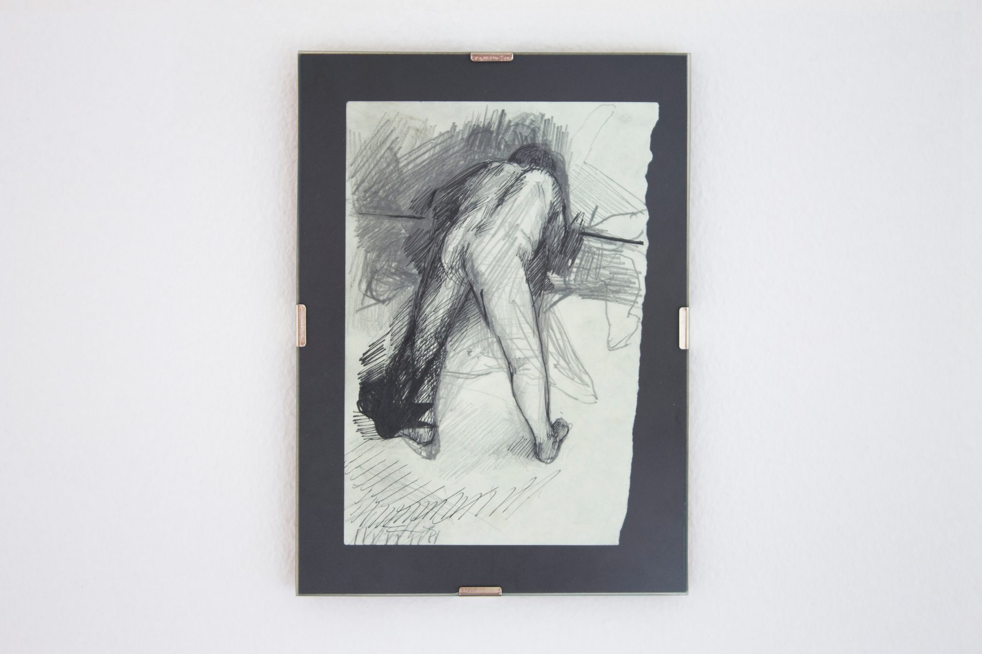 Framed pencil sketch of a bending nude figure on a white wall.
