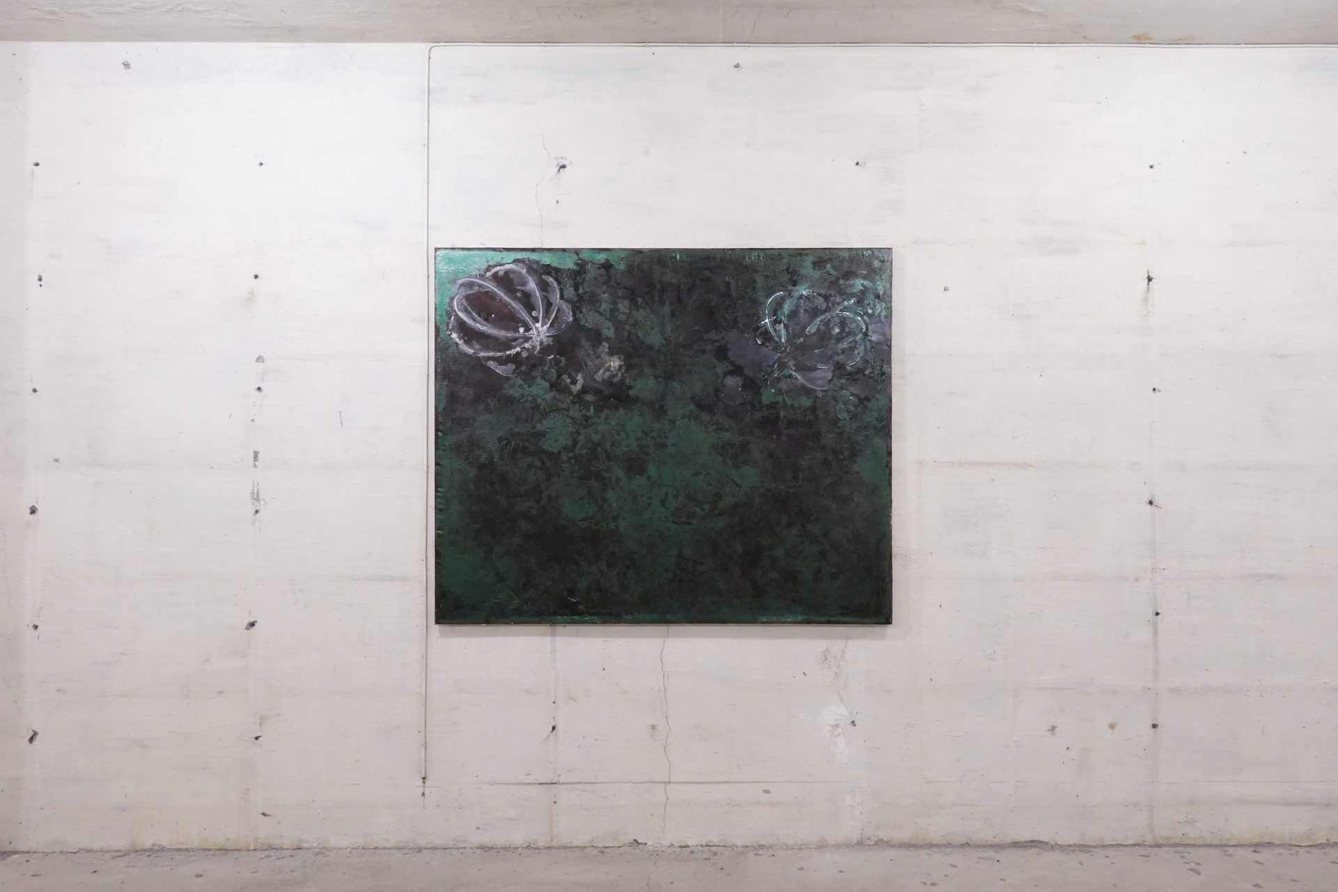 Abstract dark green painting with two light floral shapes on a concrete wall.