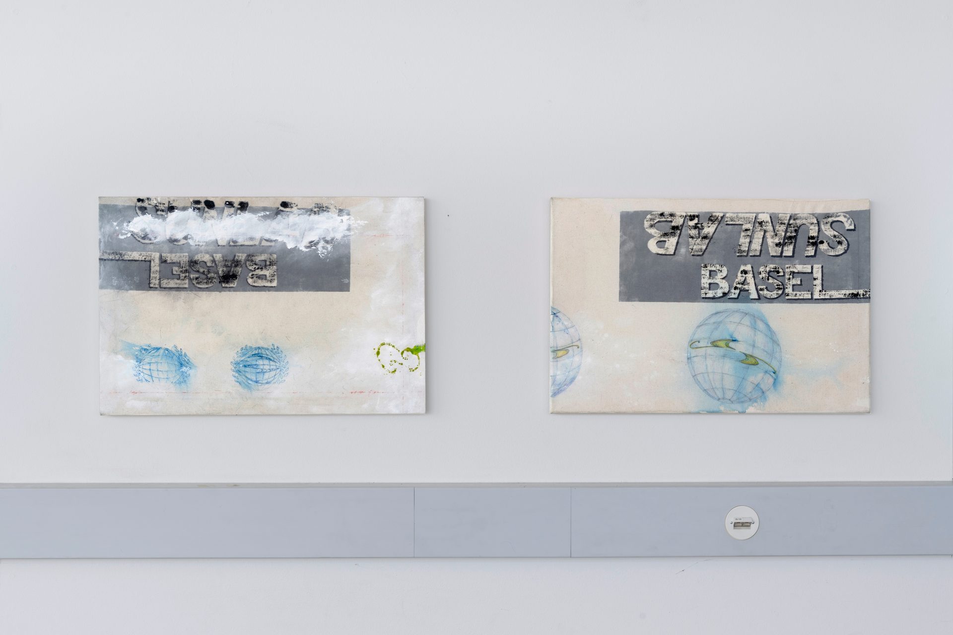 Two mixed media paintings: 'SUNLAB', 'BASEL' text (some reversed), blue globes on white wall.