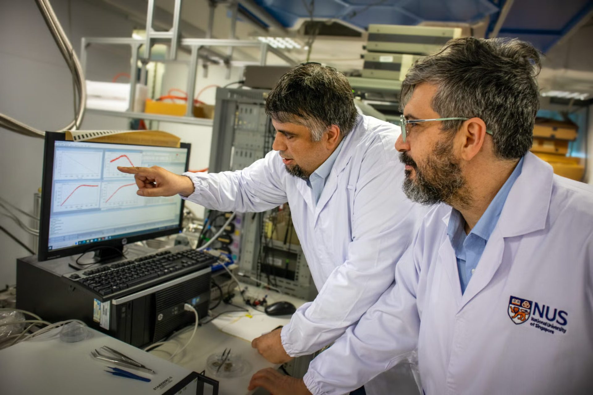 Two scientists analyze data charts in a lab (NUS).