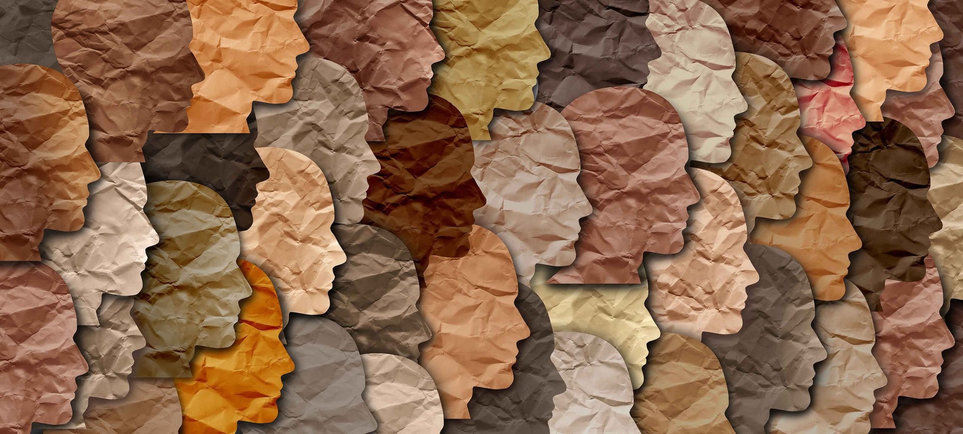 Diverse human profiles made from crumpled paper in various skin tones.