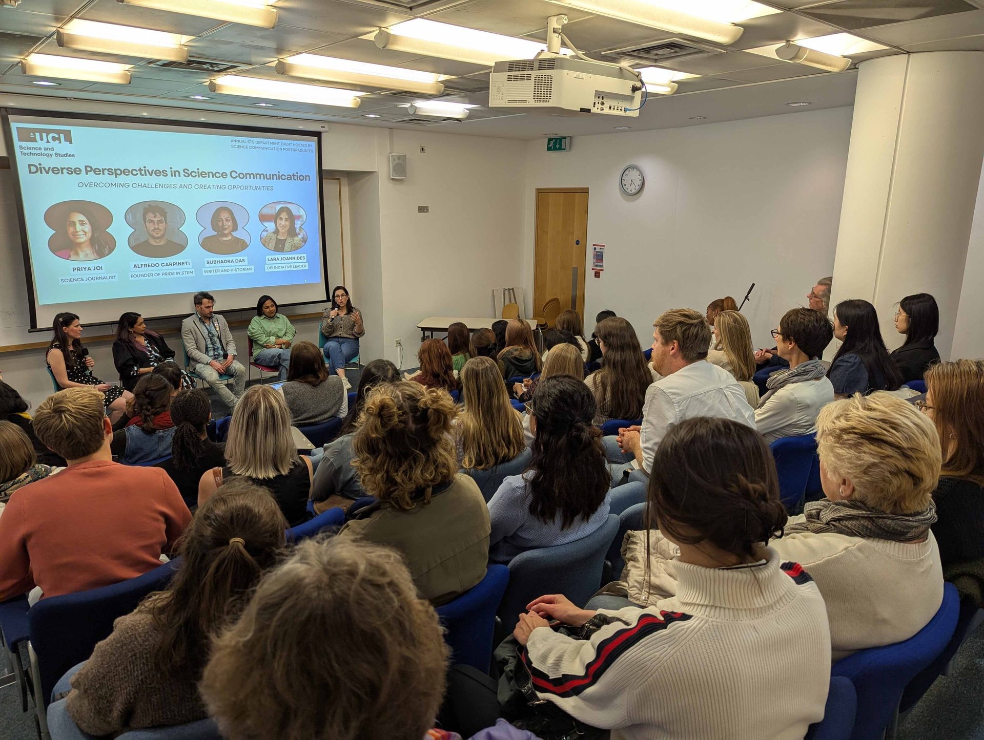 A panel discussion on science communication with five panelists on stage and a large audience.