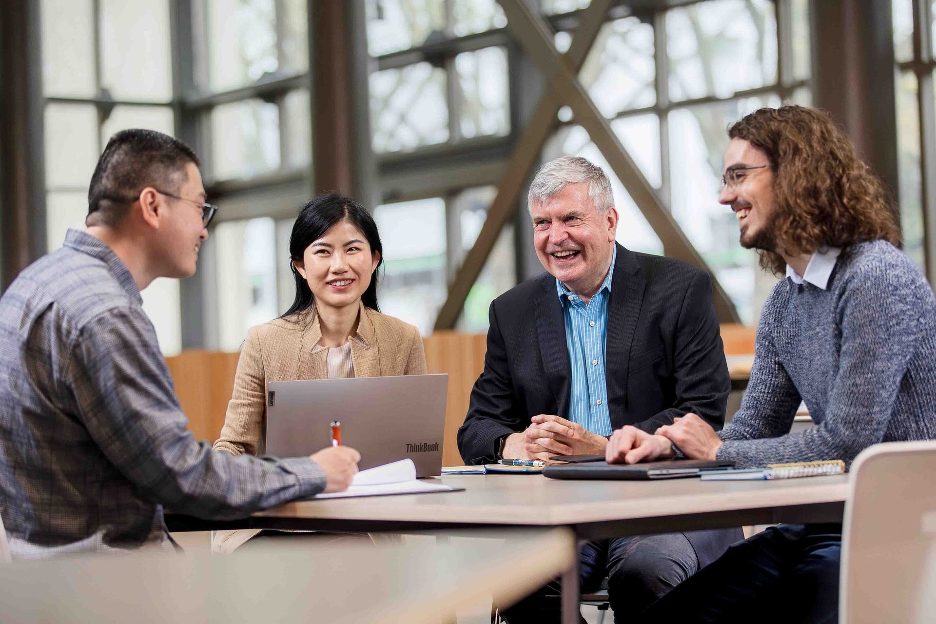 Four diverse people smiling and discussing around a table.