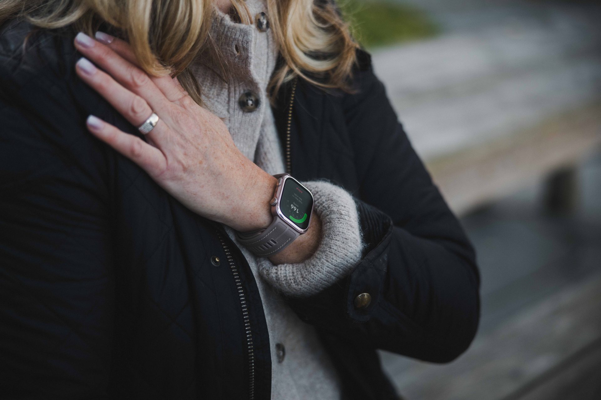 Close-up of a person's arm wearing a smartwatch and a ring on their finger.