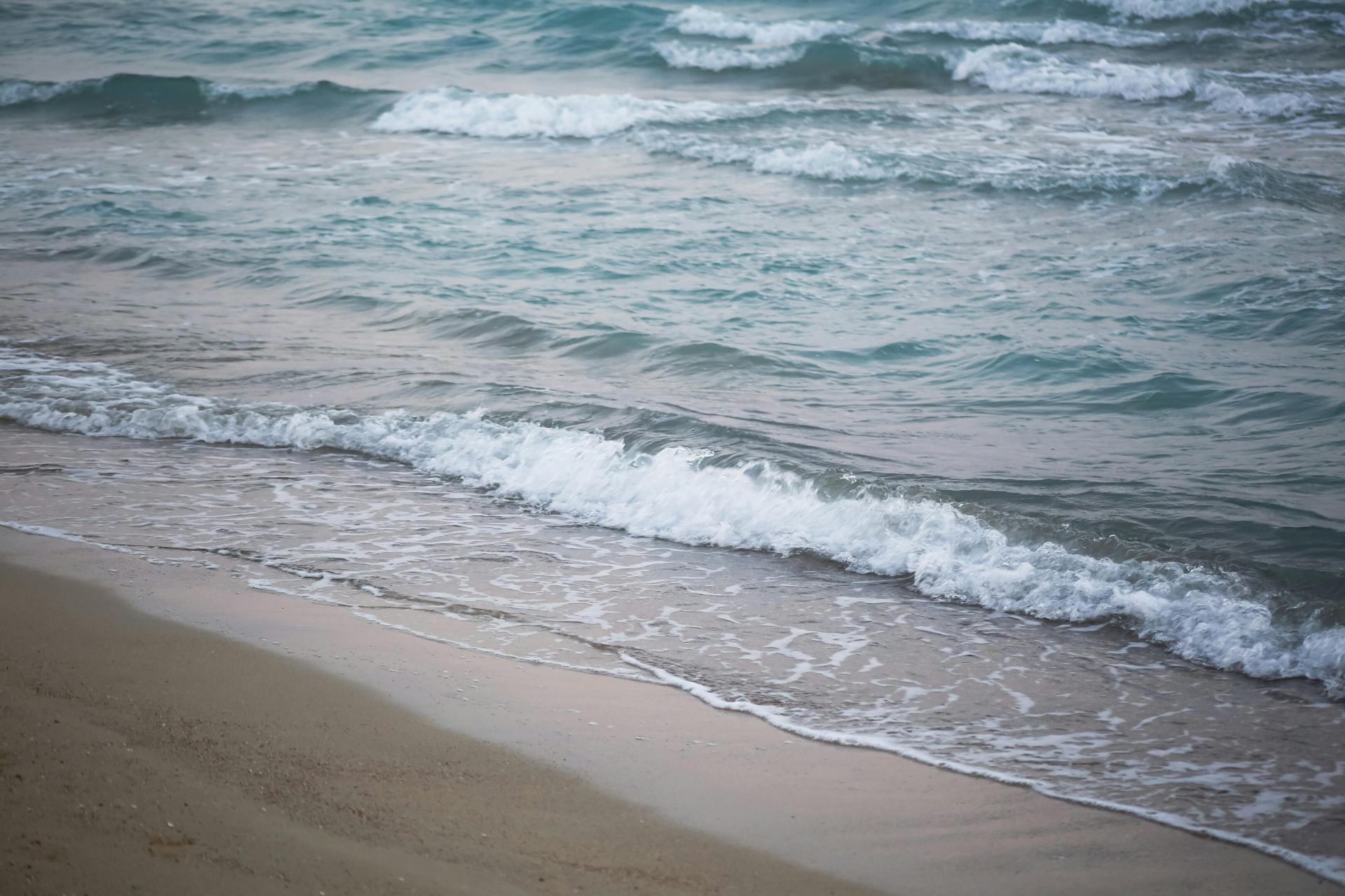 Foamy ocean waves breaking on a sandy beach.