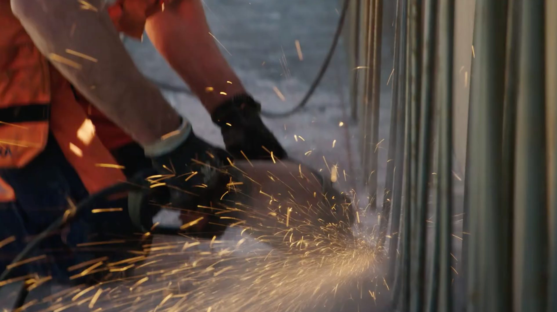 Sparks fly as a person cuts metal with a grinder.
