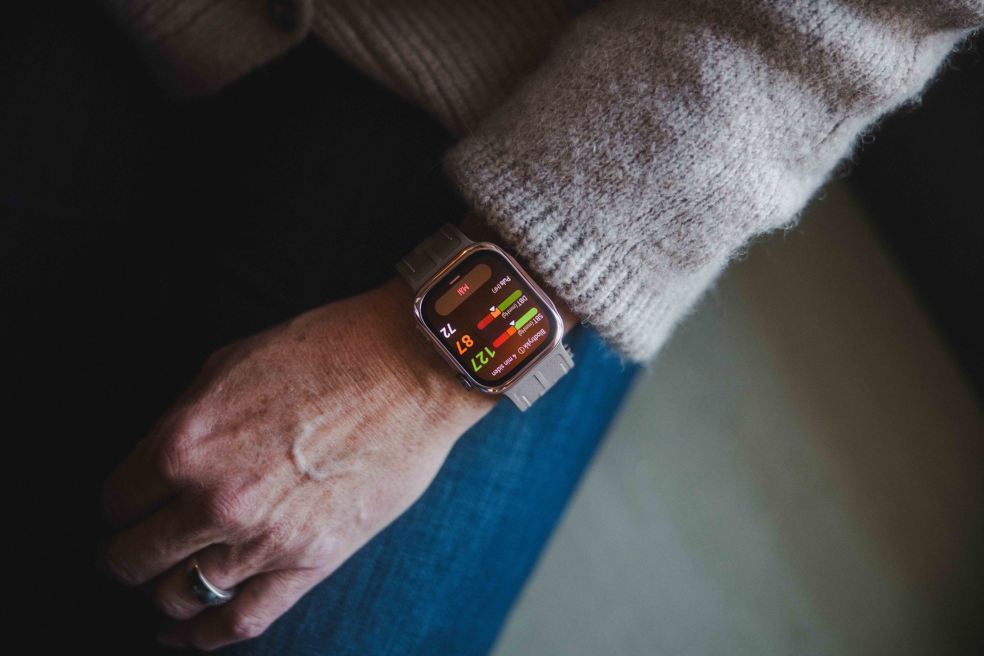 A close-up of a person's wrist wearing a smartwatch displaying health metrics like blood pressure and pulse.