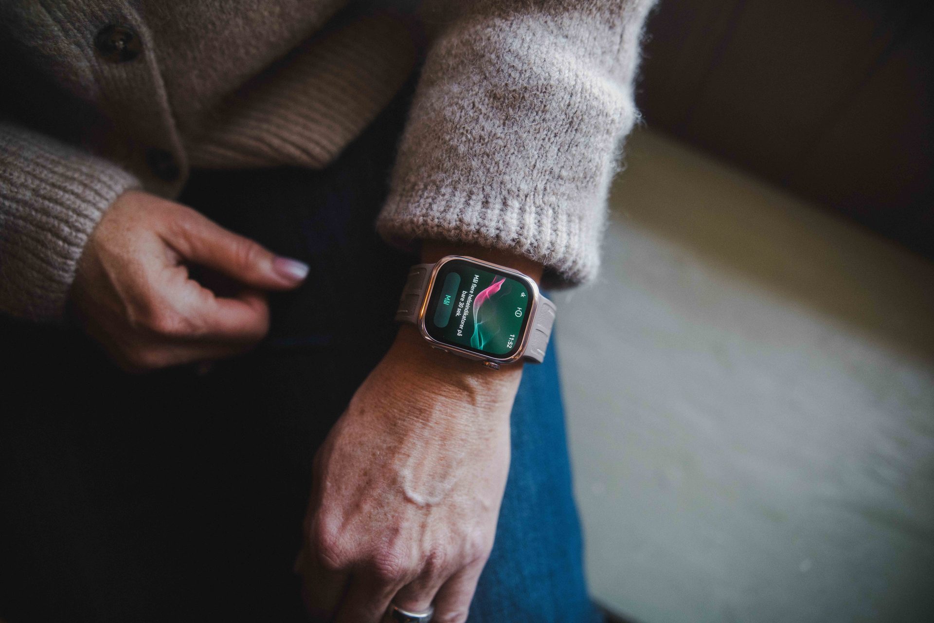 A close-up of a person's wrist wearing a smartwatch displaying a notification in Norwegian.