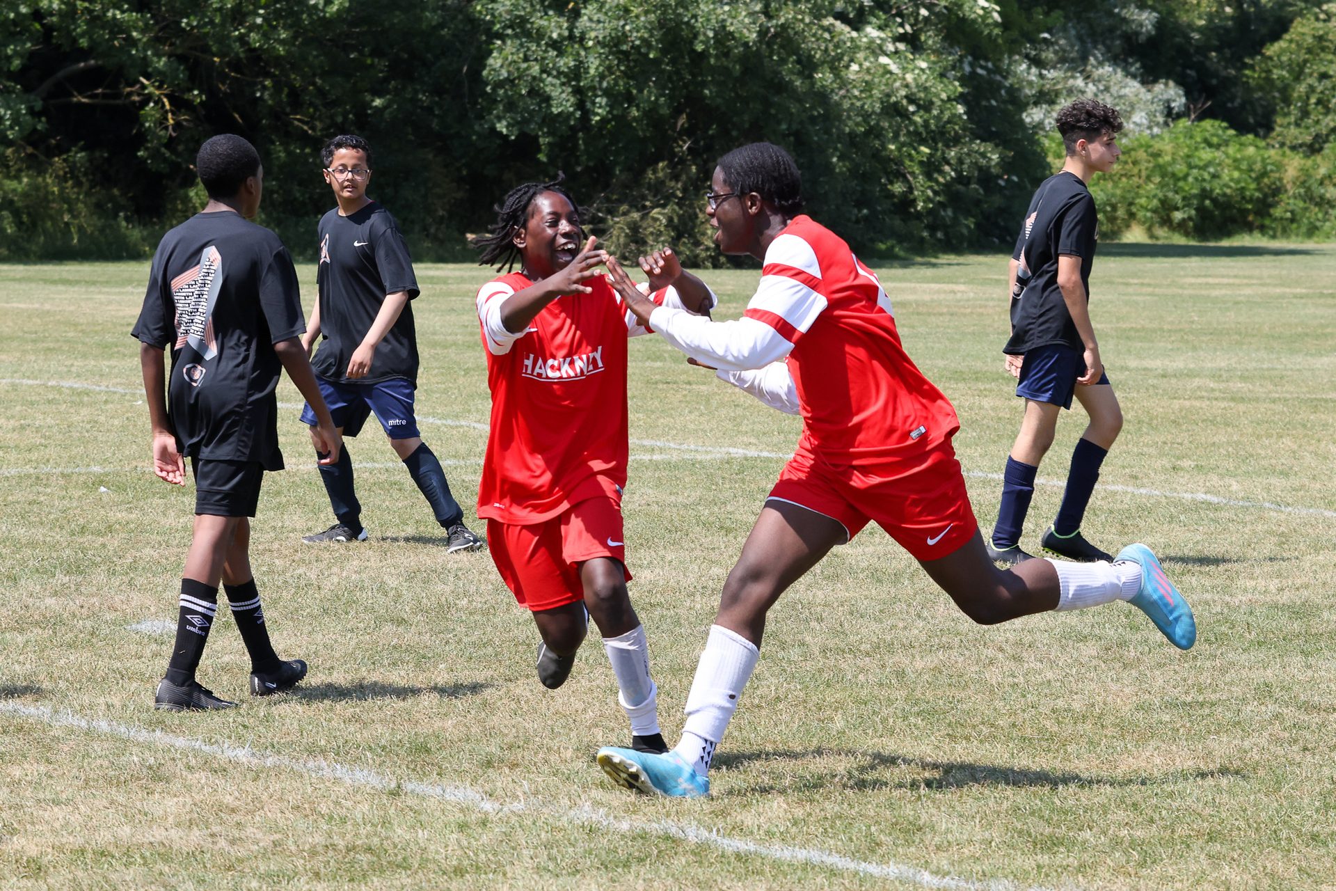 2 black boys cheering on a football pitch