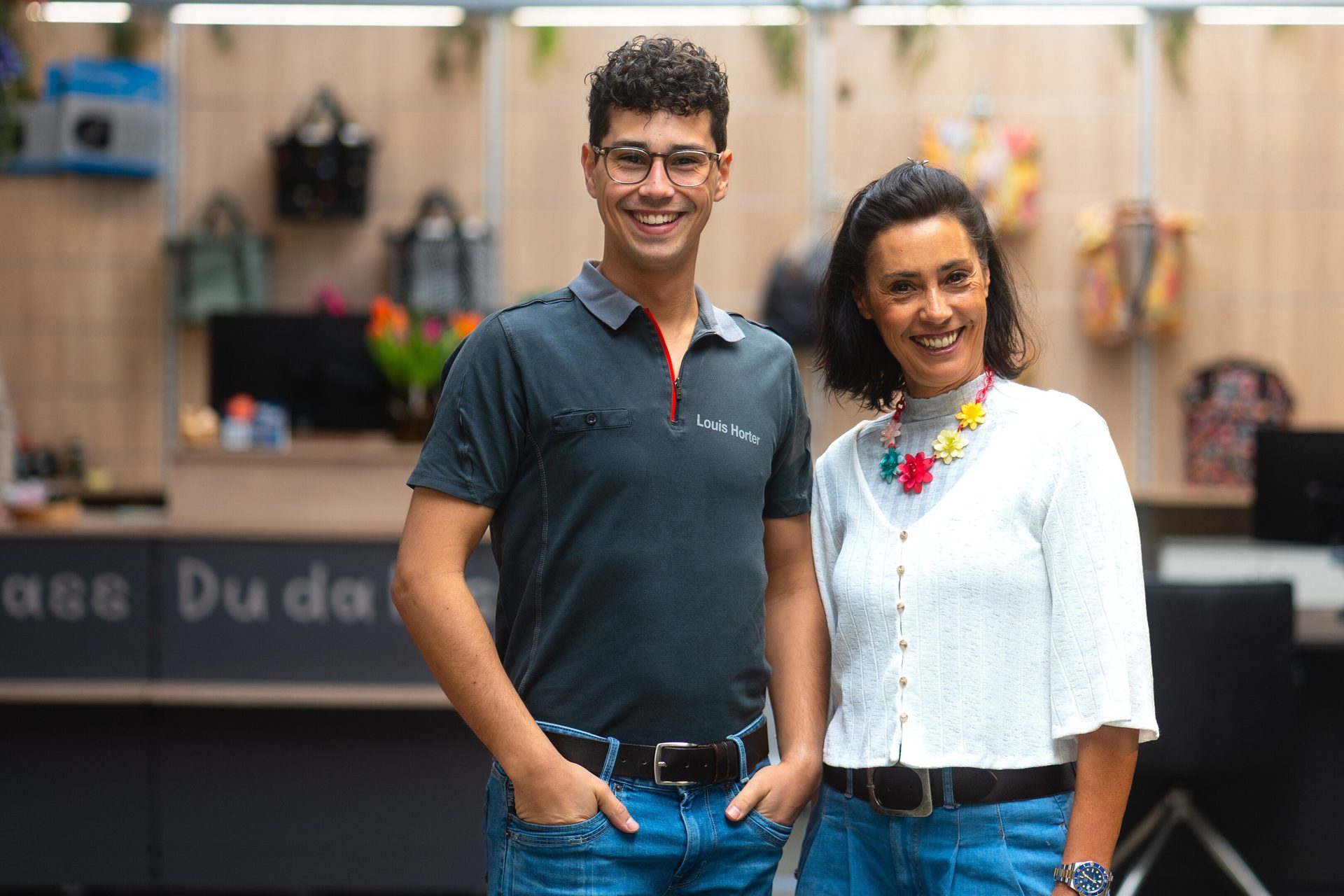 A smiling man wearing a "Louis Horter" polo shirt and a smiling woman posing together in an office.