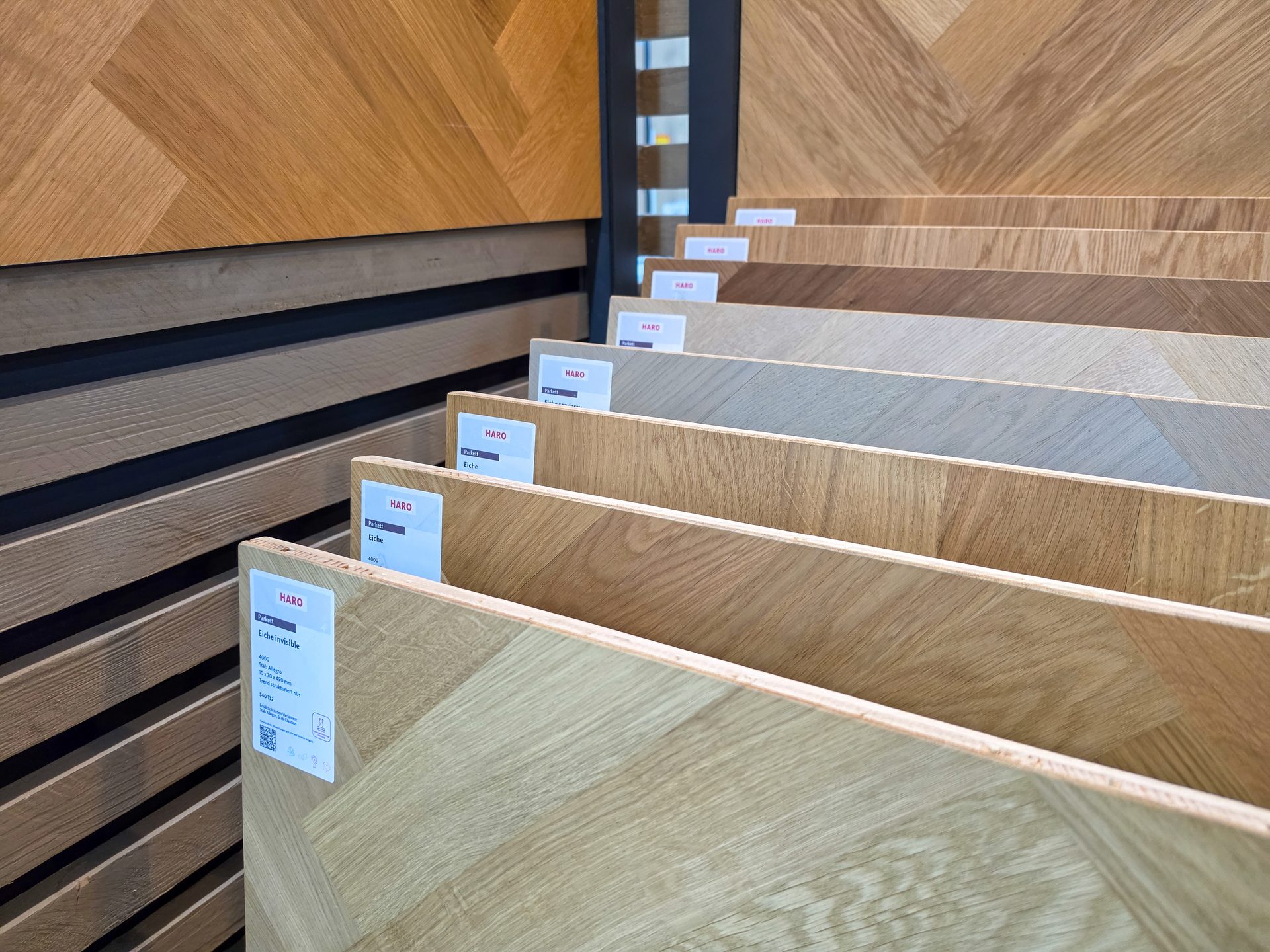 A display of various wooden parquet flooring samples with Haro brand labels, showcasing different finishes.