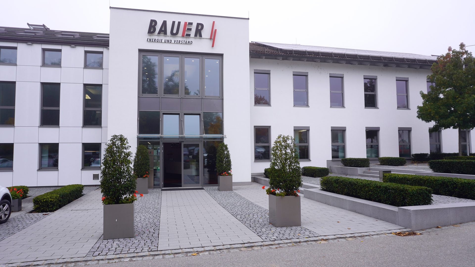 Exterior view of the white BAUER building with large windows, landscaping, and solar panels.