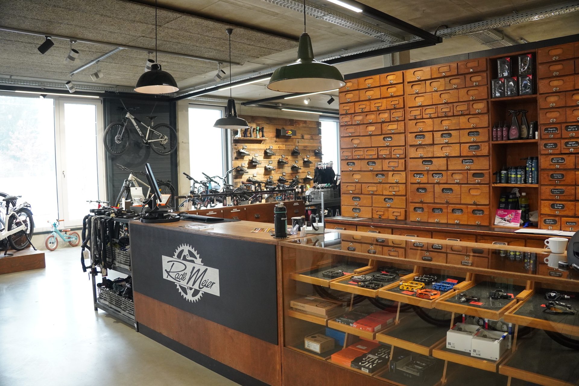 Interior view of a bike shop with a "Rade Meier" counter, display cases, and a wall of wooden drawers.