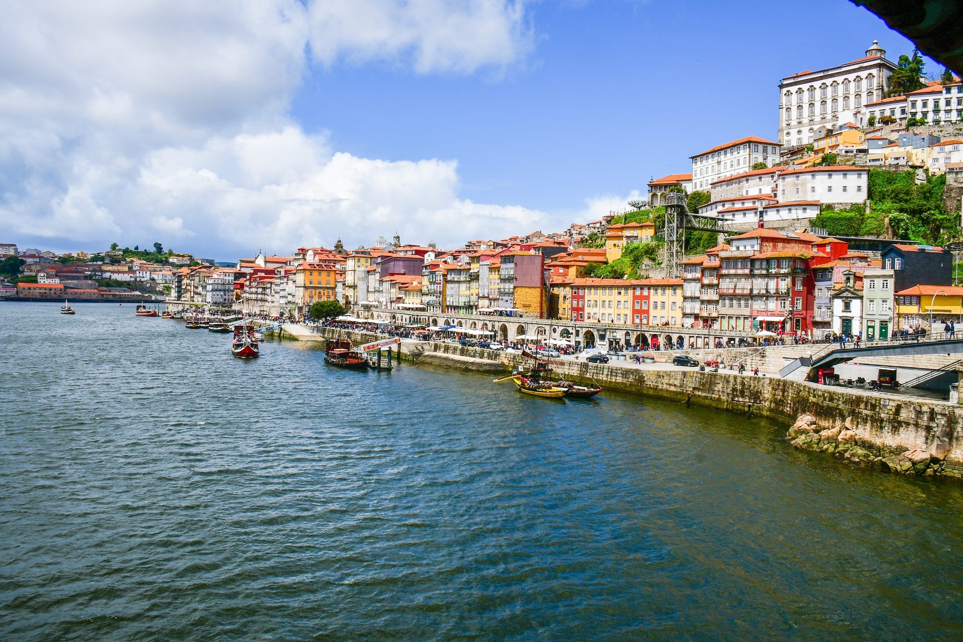 Vibrant Porto cityscape along the Douro River, featuring colorful buildings and traditional boats.