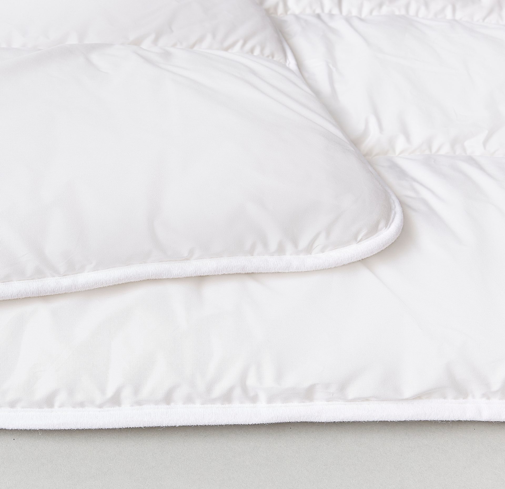 White quilted blanket with a soft, fuzzy trim.