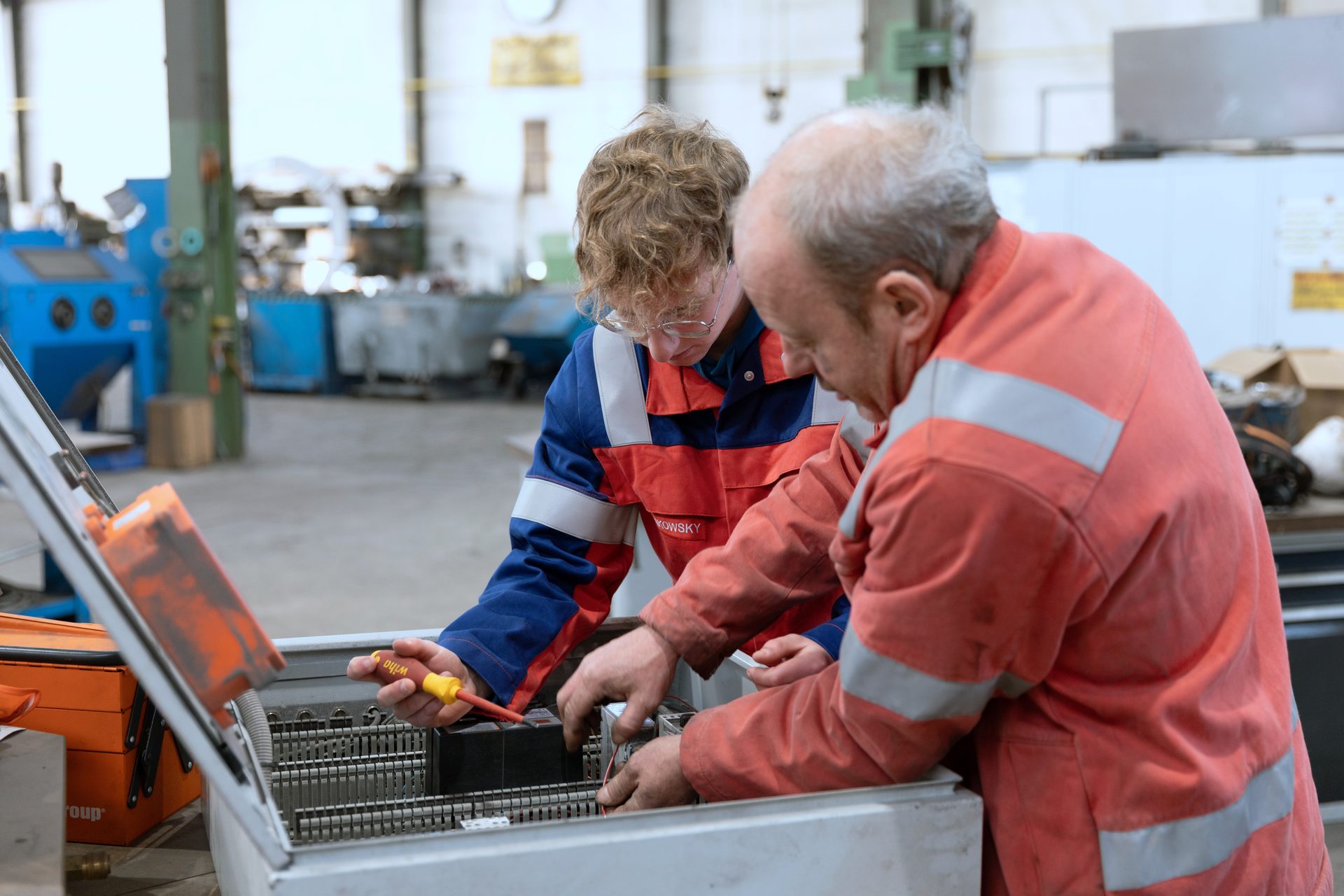 Two industrial workers troubleshooting an electrical panel.