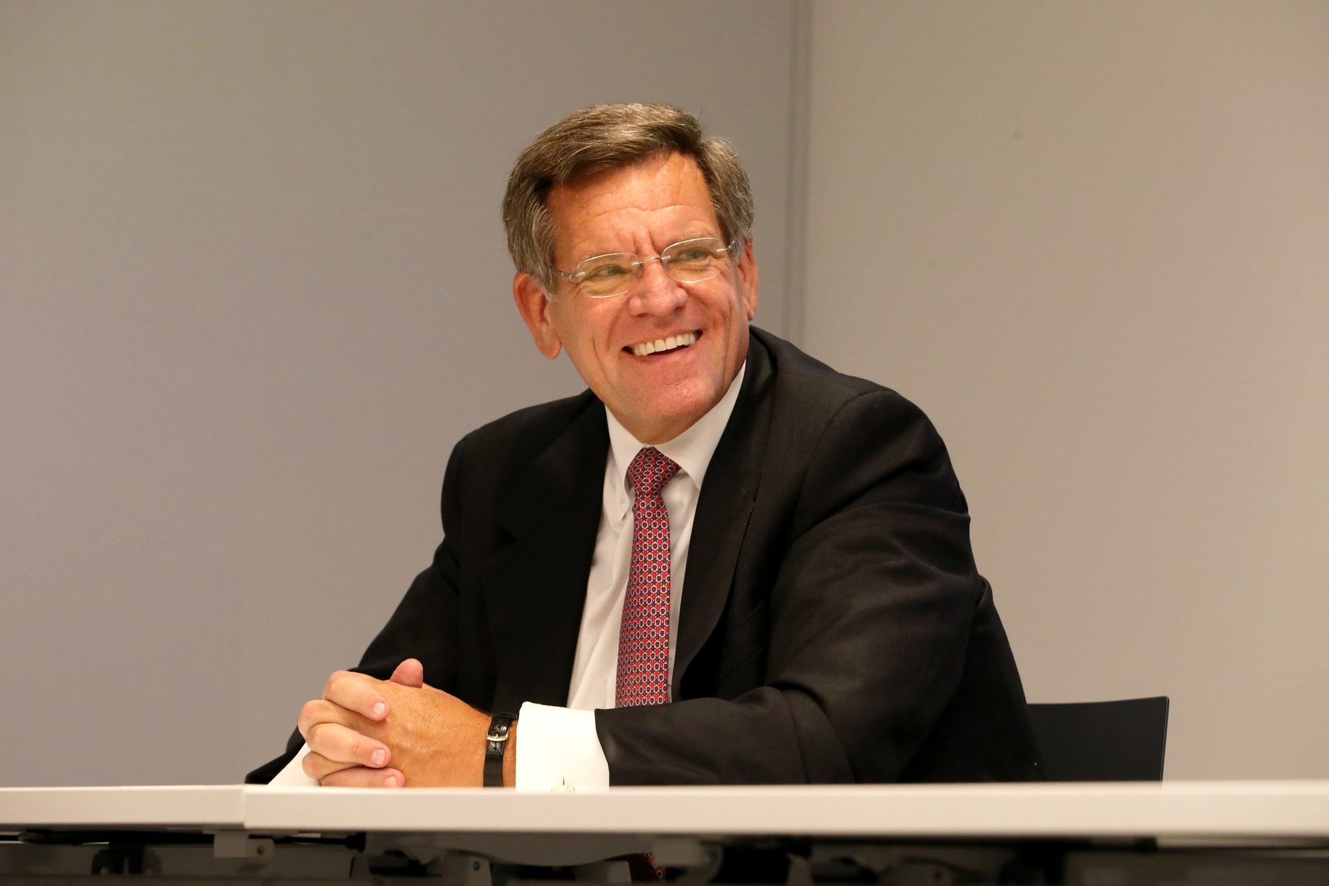 Dress shirt, Smile, Tie, Table, Suit, Gesture, Spokesperson