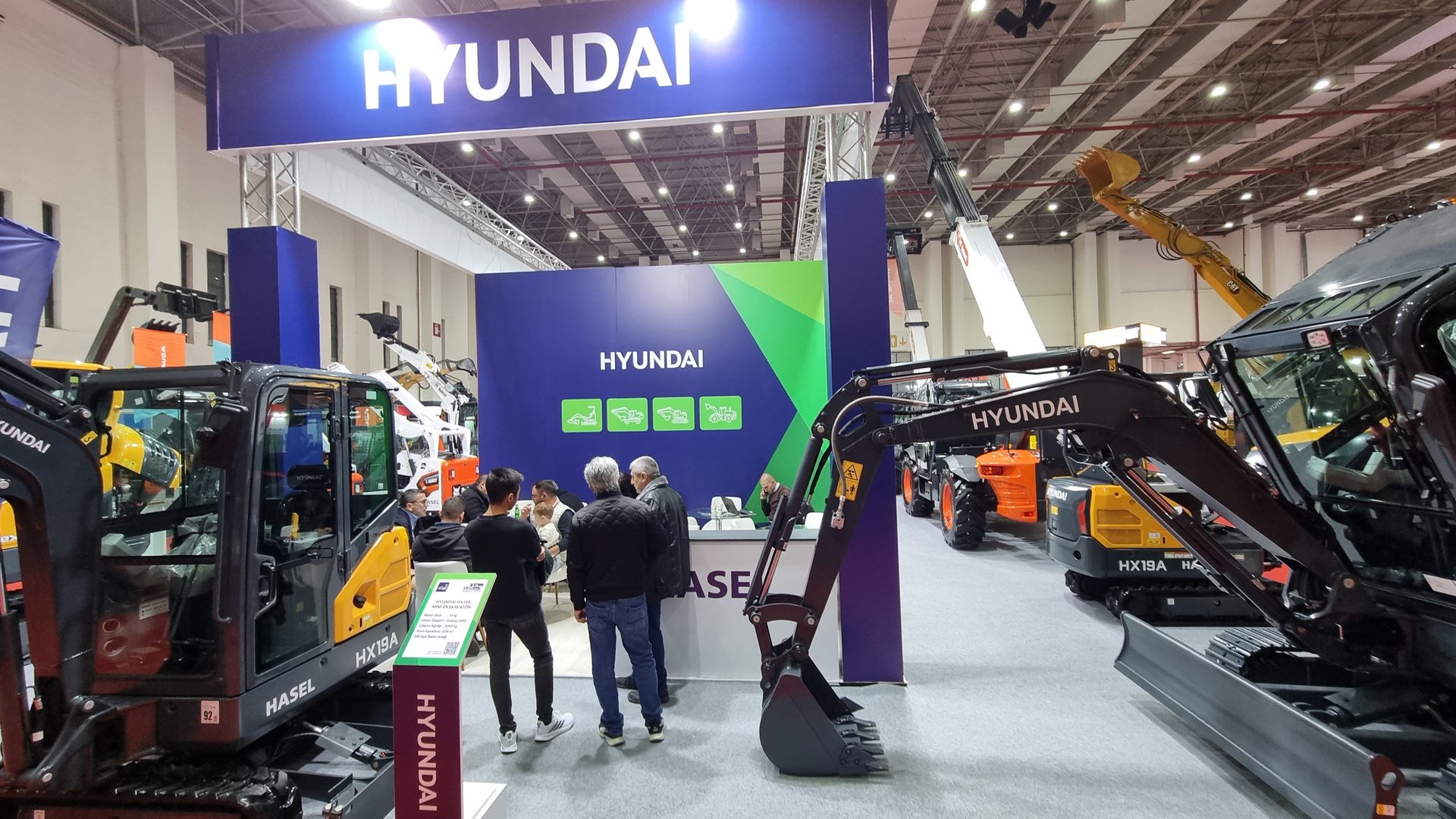 A Hyundai exhibition stand featuring various construction excavators and heavy machinery with visitors.