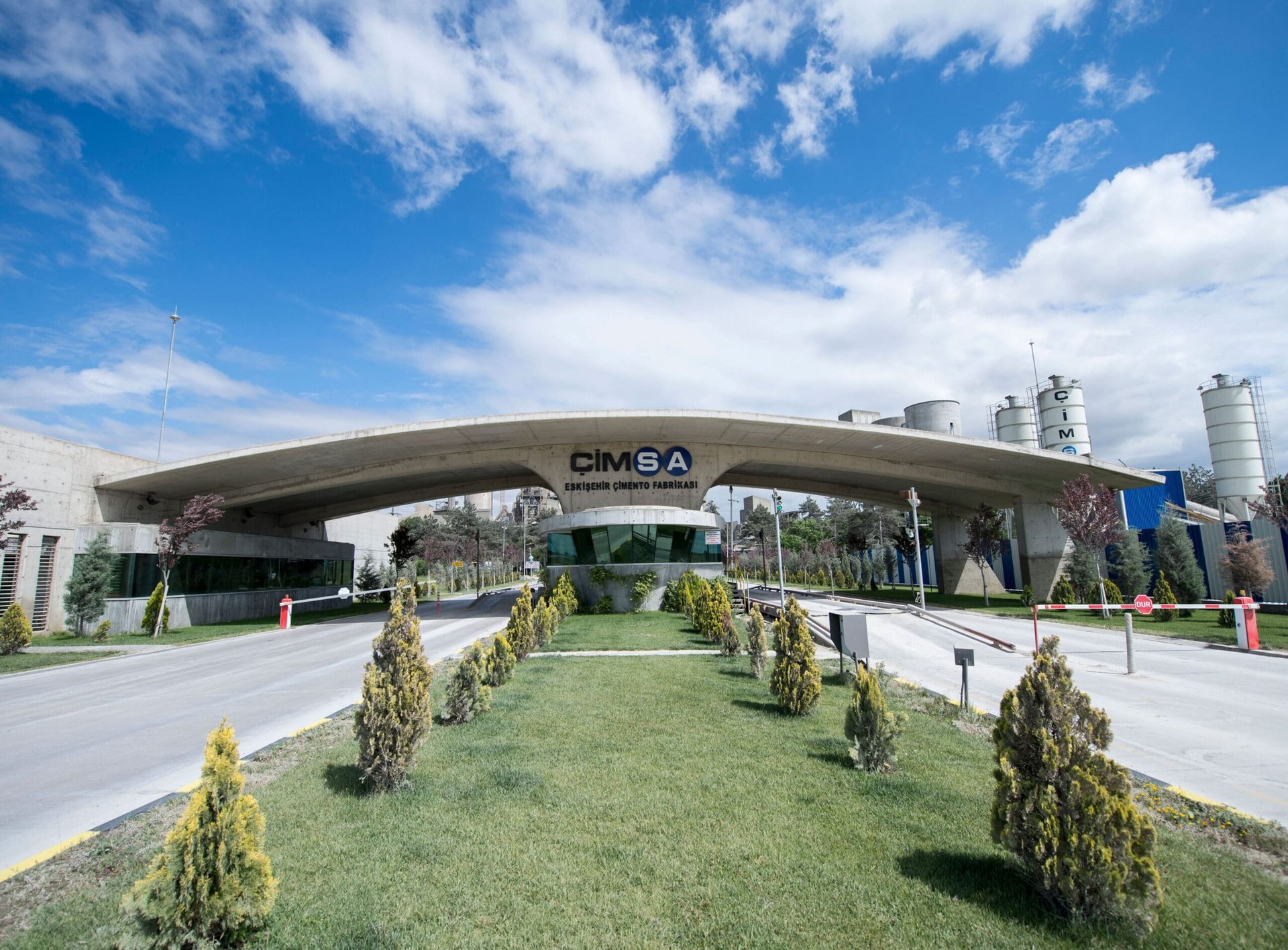 Cimsa Eskisehir Cement Factory entrance, featuring a concrete archway, company sign, and a guardhouse.