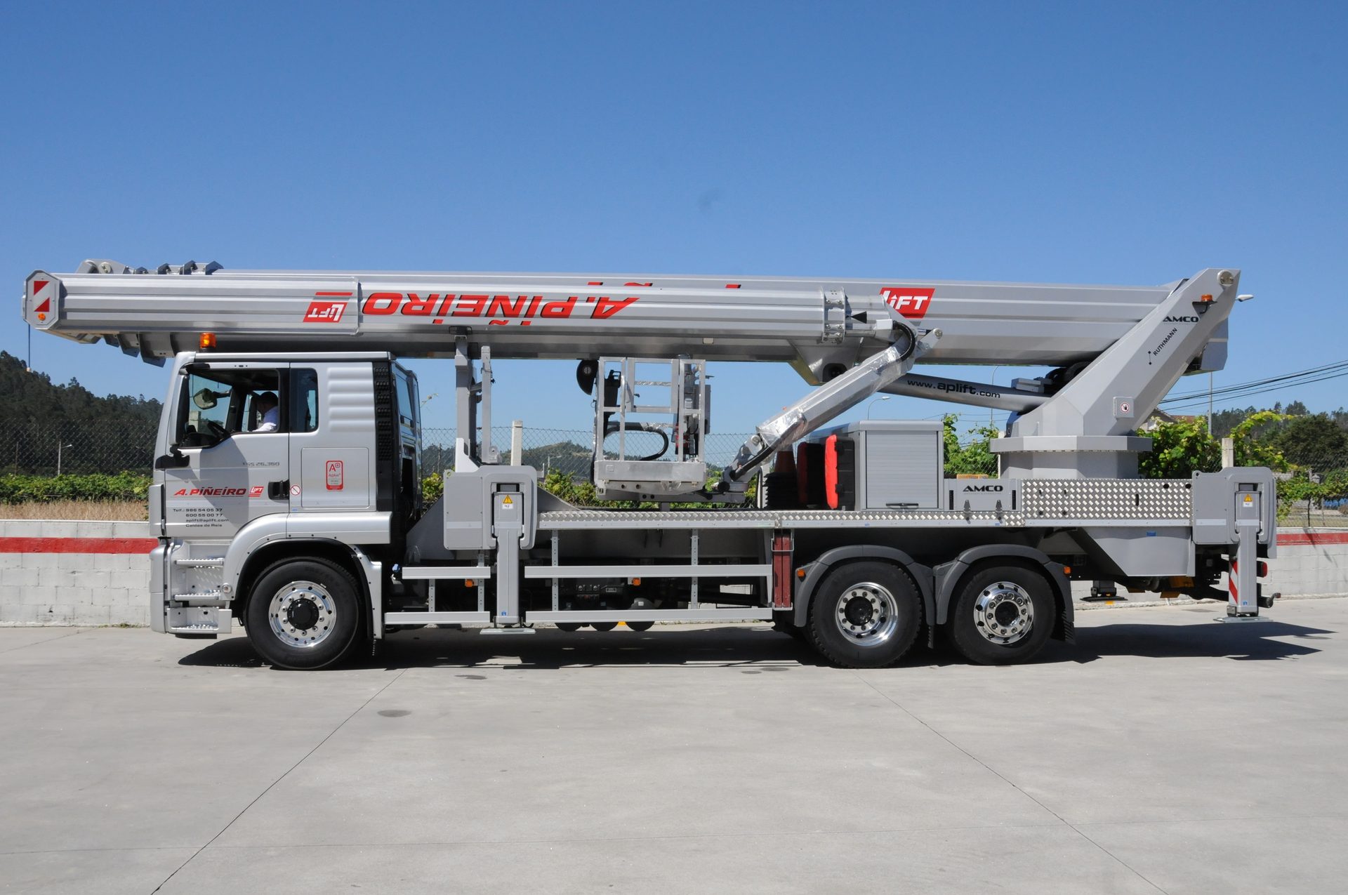 A large grey truck with an extended aerial work platform and long lift arm parked on pavement.