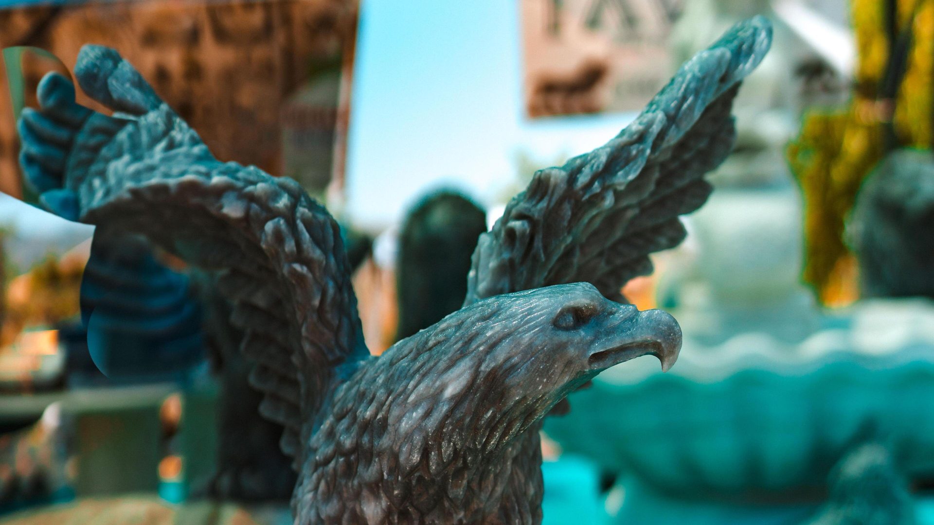 Detailed dark gray stone eagle statue with wings spread, looking right.
