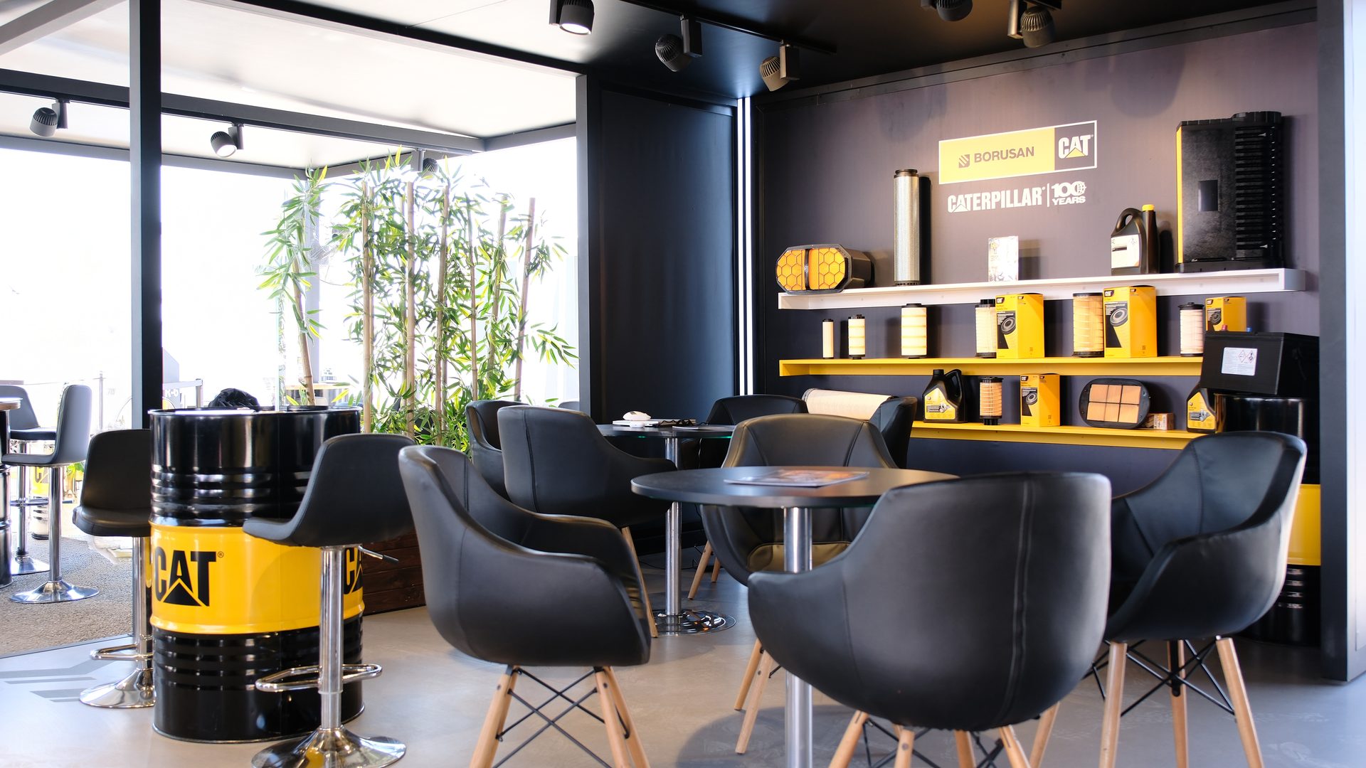 Borusan CAT showroom with lounge seating, product displays, and branded barrel tables.