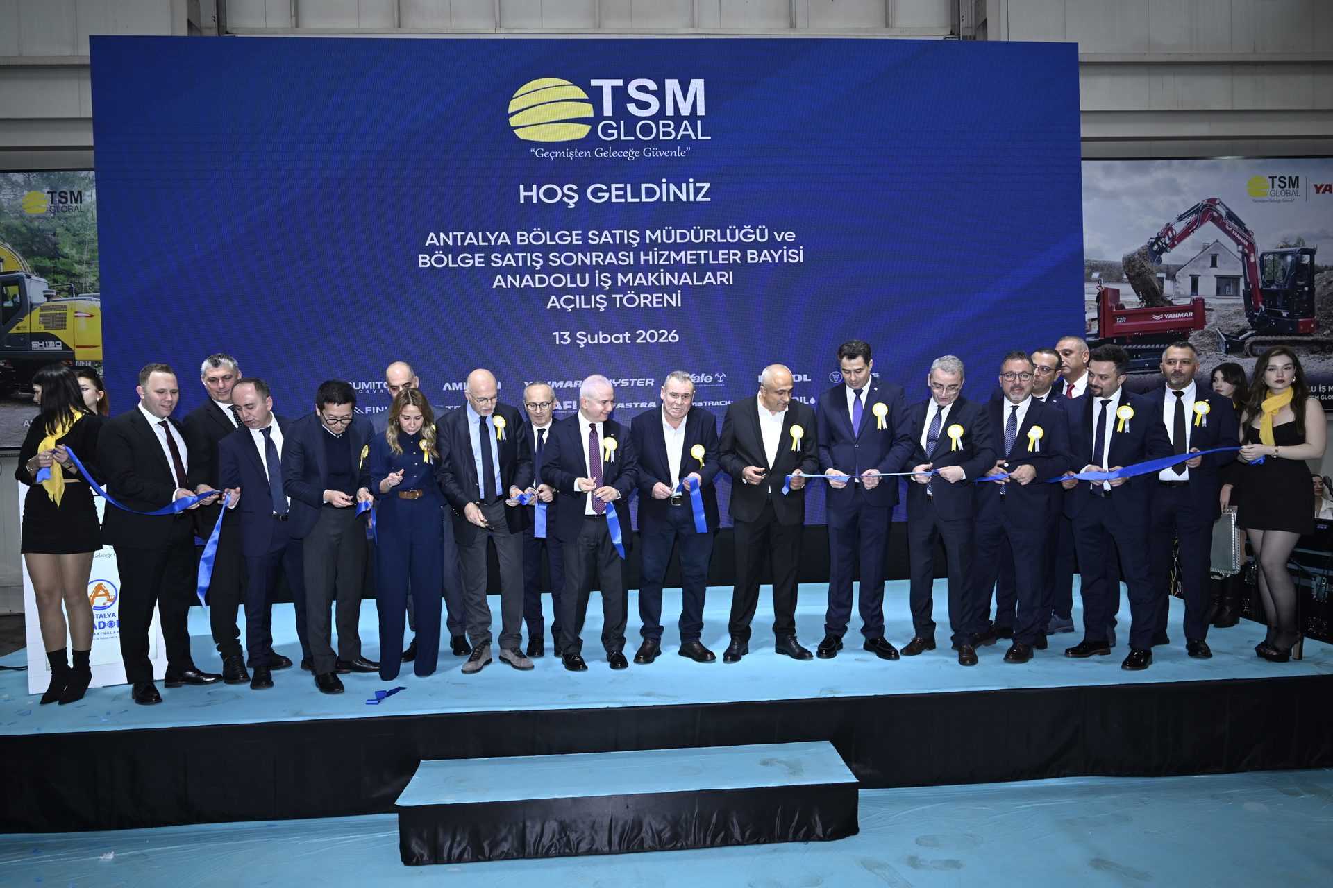 A group of people cutting a blue ribbon at the opening ceremony for TSM Global's new dealership in Antalya.