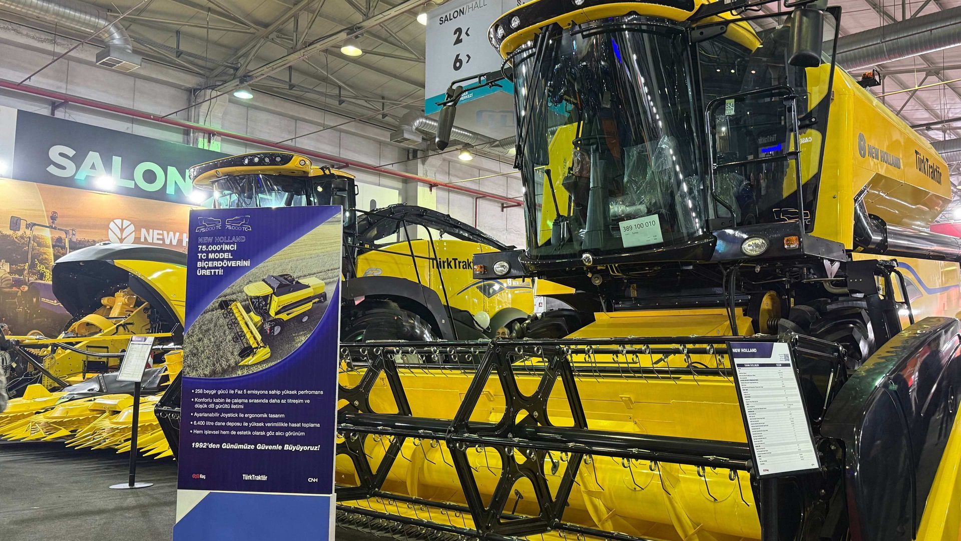 Two yellow New Holland combine harvesters on display at an exhibition, with Turkish text.